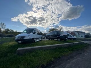 Three vans parked on grass, under a partly cloudy sky.