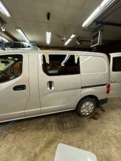 Silver cargo van parked inside a garage, open side door.