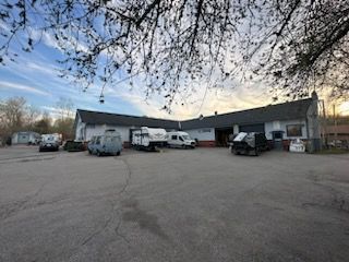 A small, low-slung building with vehicles parked outside under a partly cloudy sky.