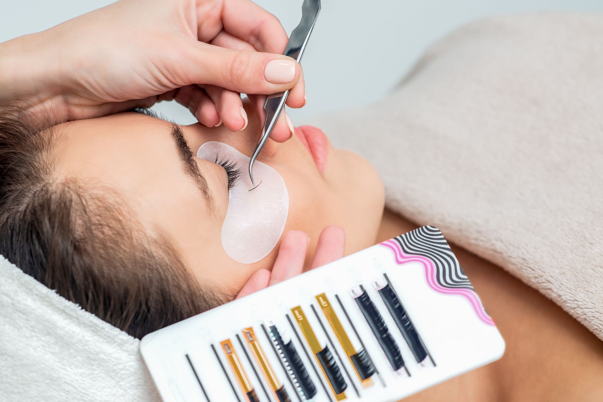 A woman is getting eyelash extensions in a beauty salon.