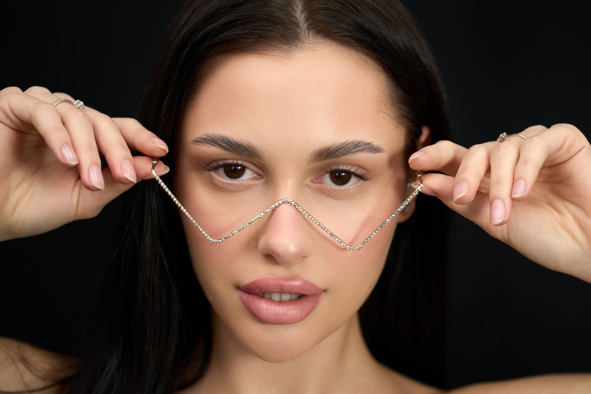 A woman is wearing a pair of glasses with a chain around her nose.