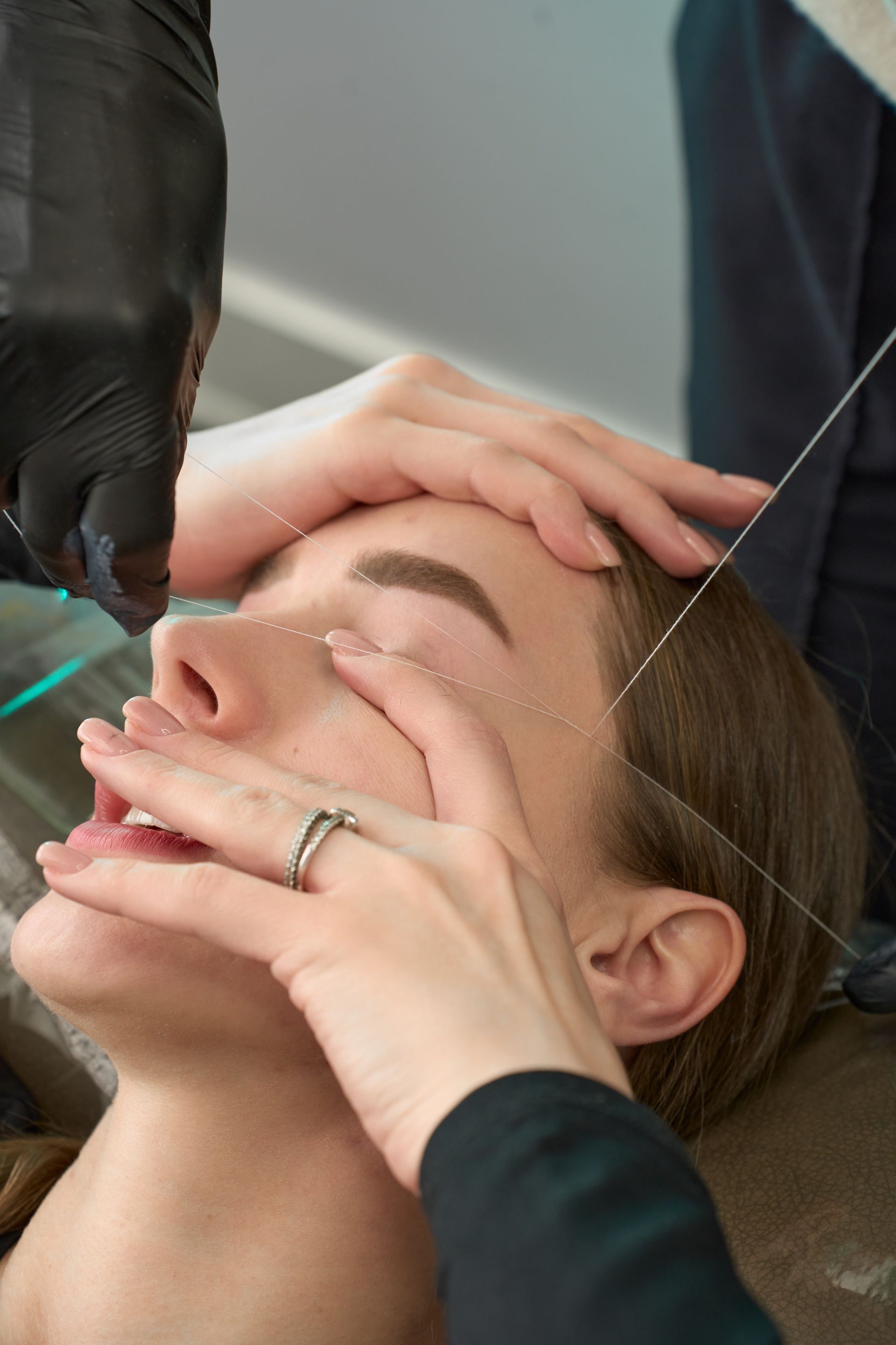 A woman is getting her eyebrows threaded in a beauty salon.