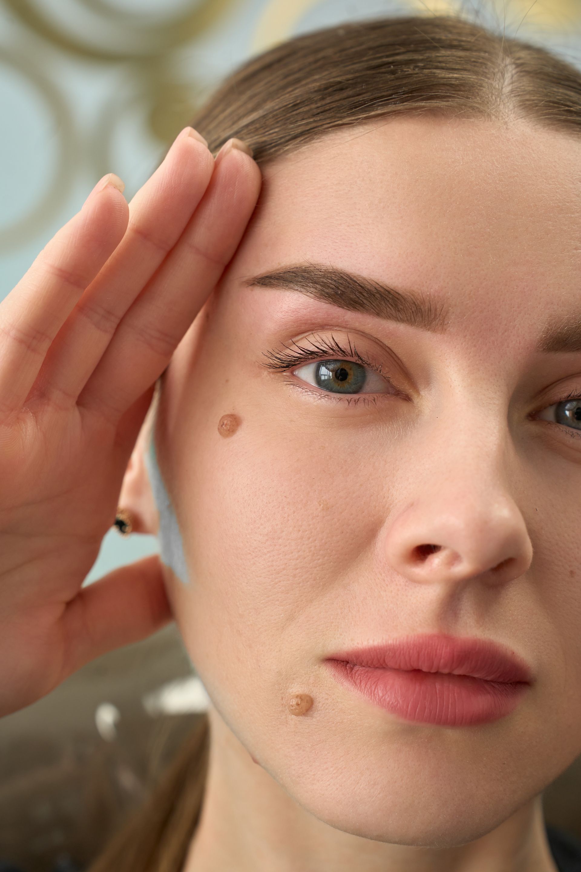 A close up of a woman 's face with a hand on her forehead.