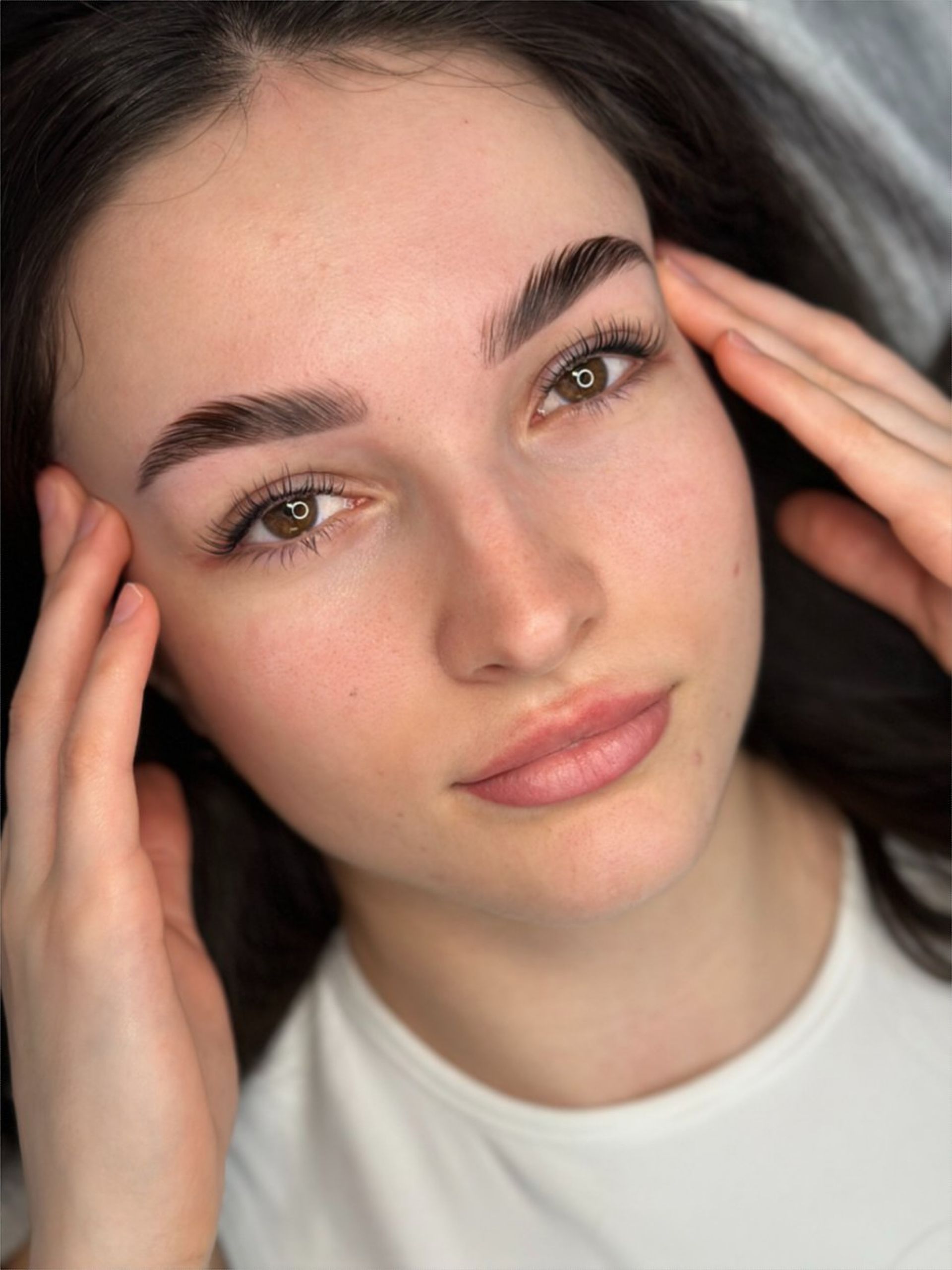 A close up of a woman 's face with her hands on her forehead.