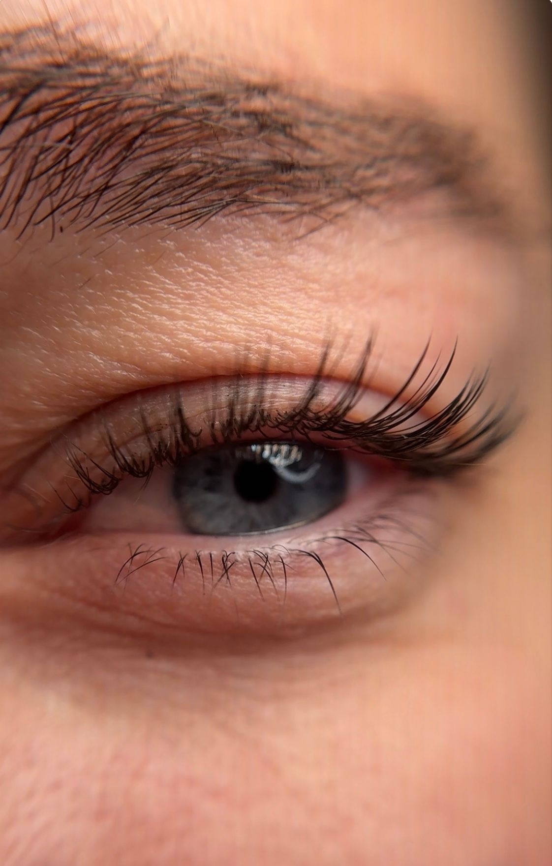 A close up of a woman 's blue eye with long eyelashes.