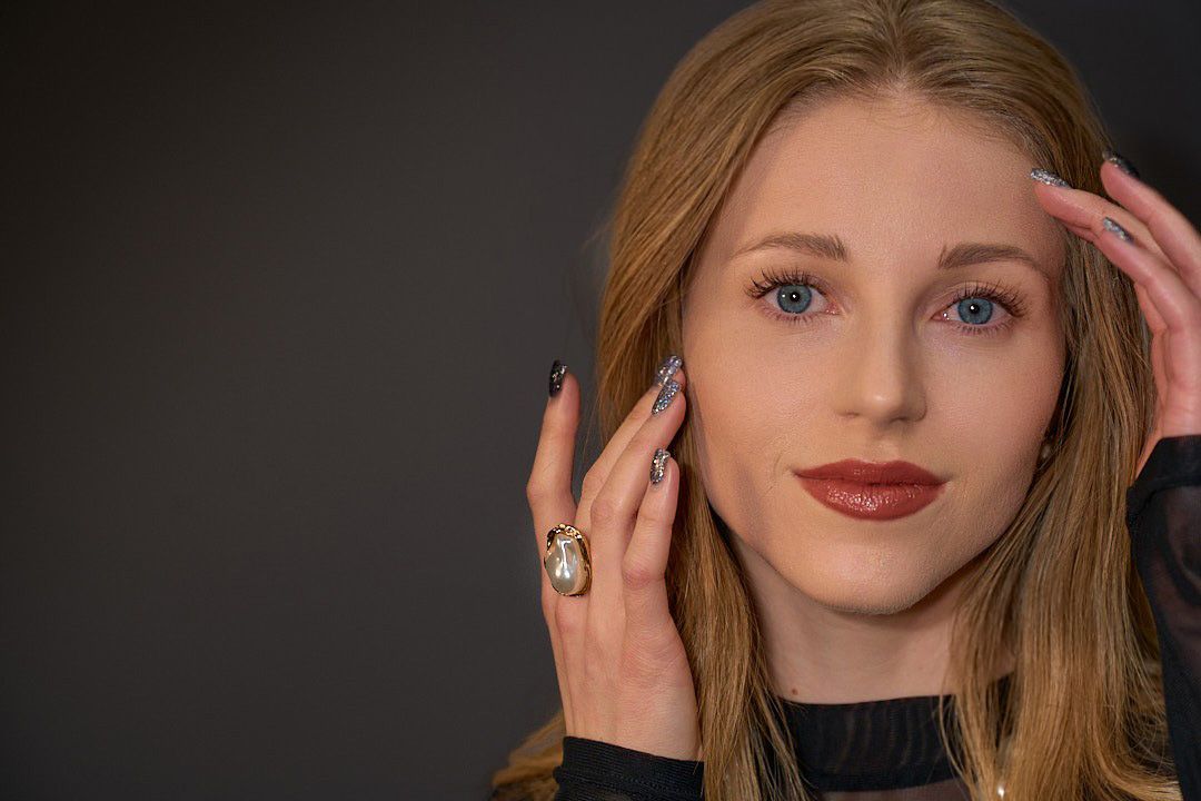 A close up of a woman 's face with a ring on her finger.