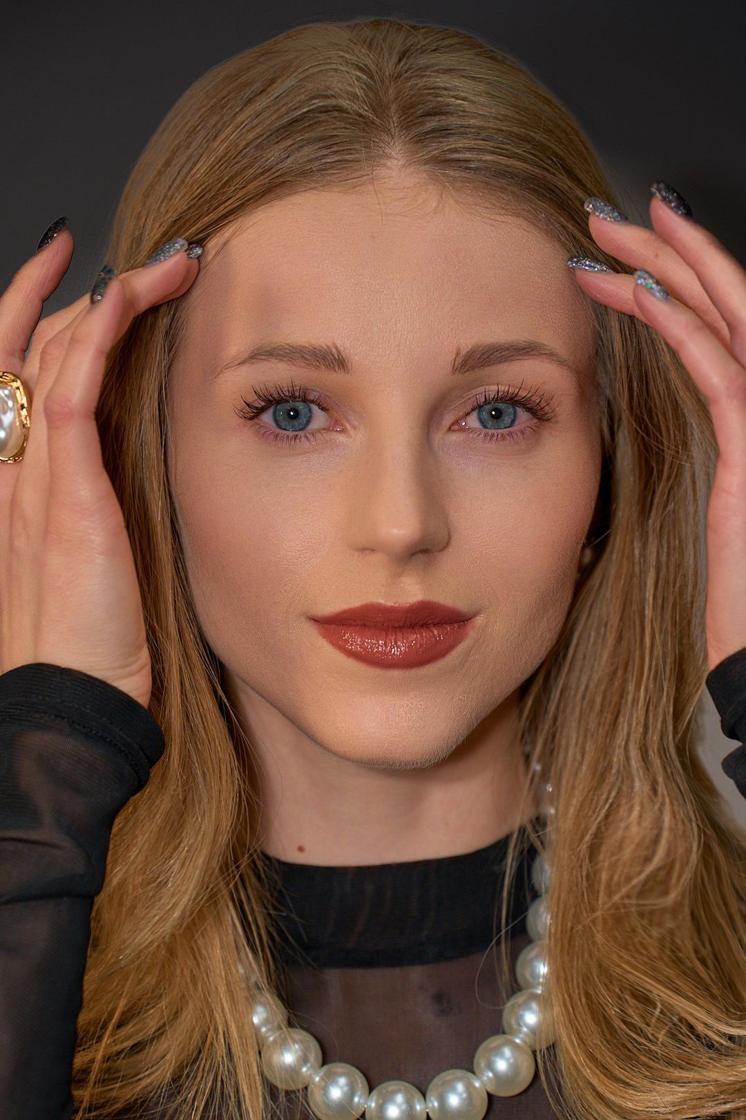 A close up of a woman wearing a pearl necklace and a ring.