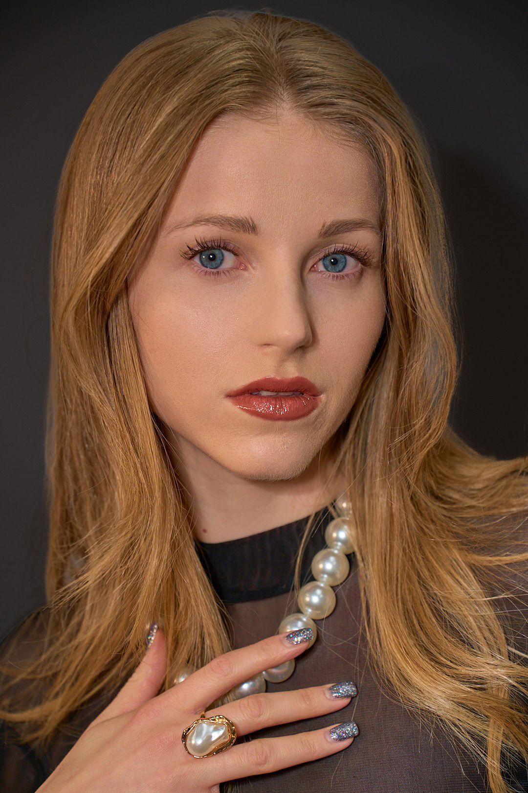 A close up of a woman wearing a pearl necklace.