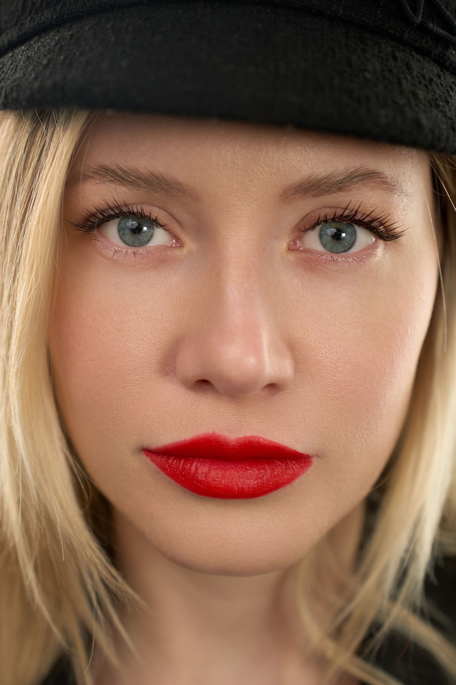 A close up of a woman wearing a hat and red lipstick