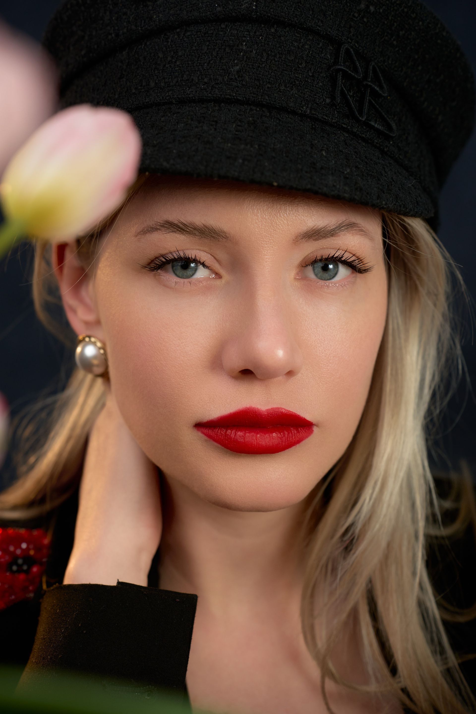 A close up of a woman wearing a hat and red lipstick.