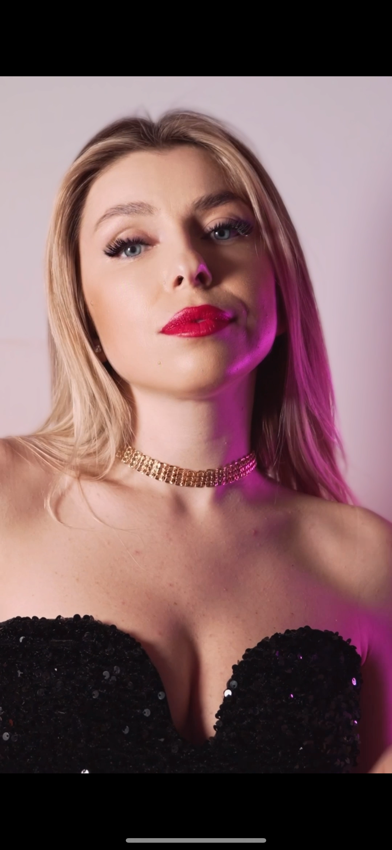 A close up of a woman wearing a choker and a black dress.