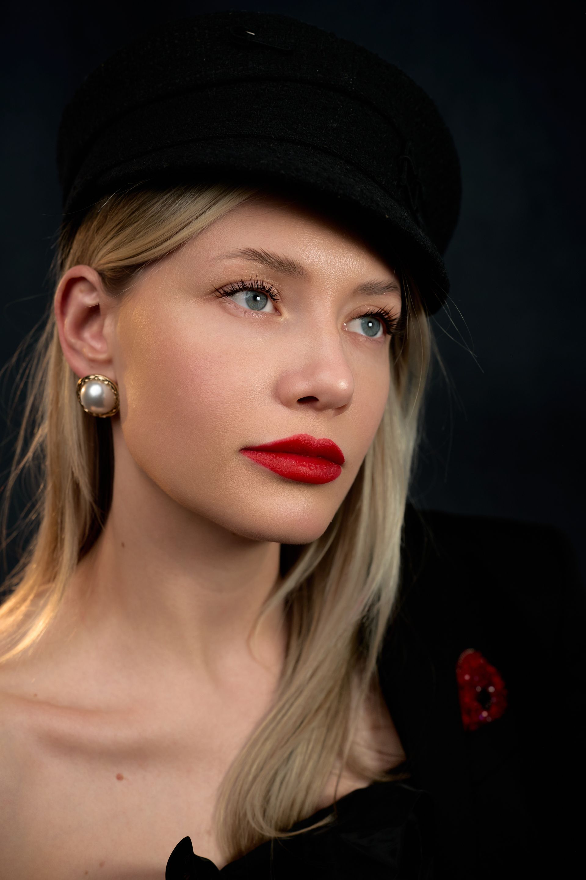 The woman is wearing a black hat and red lipstick.