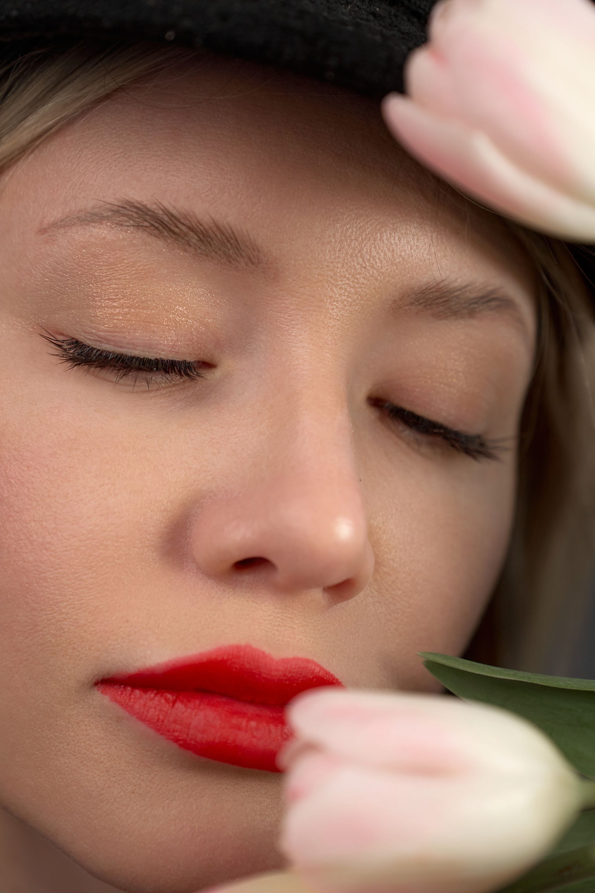 A close up of a woman smelling a flower with her eyes closed.