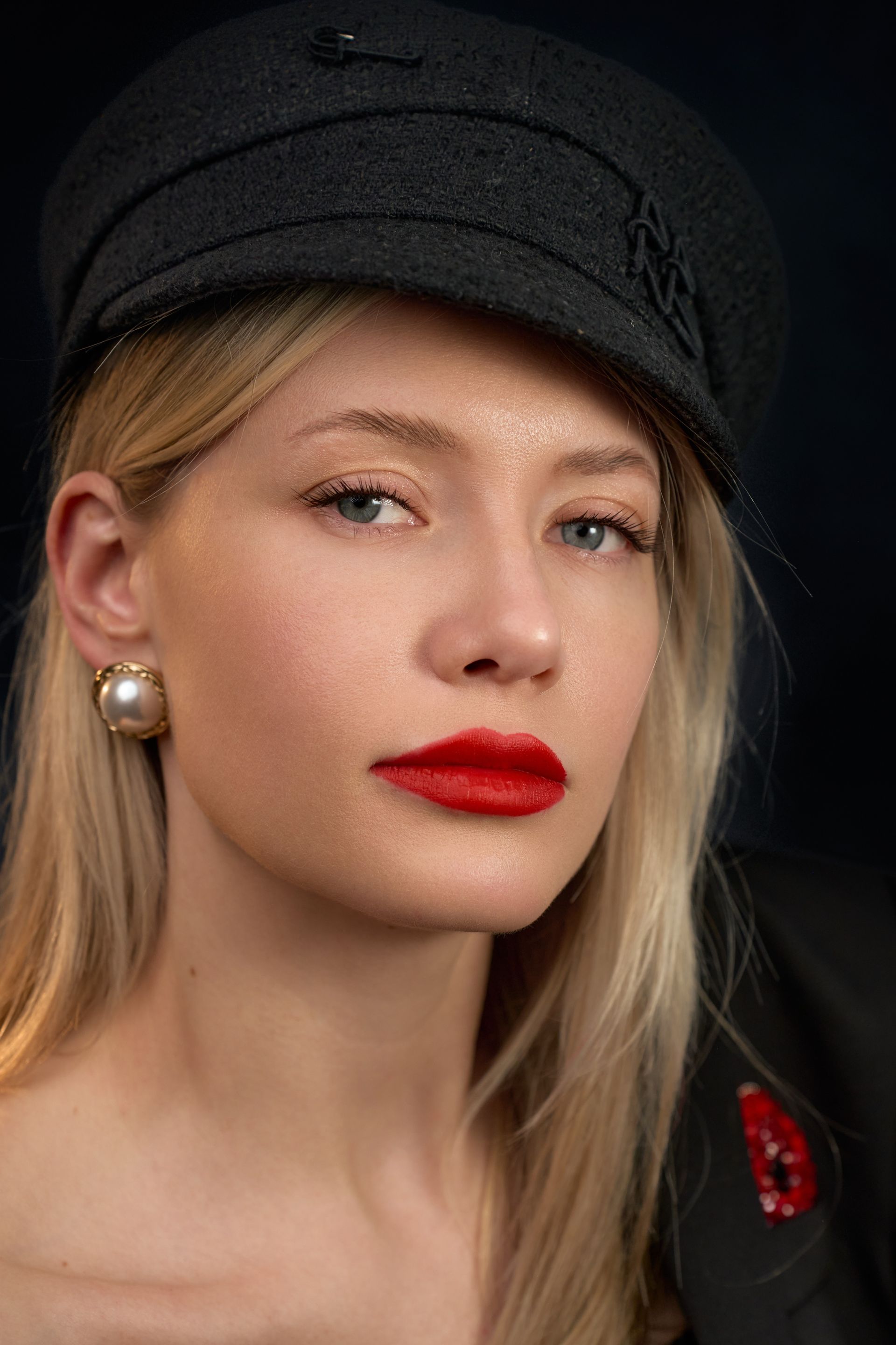 A close up of a woman wearing a hat and red lipstick.