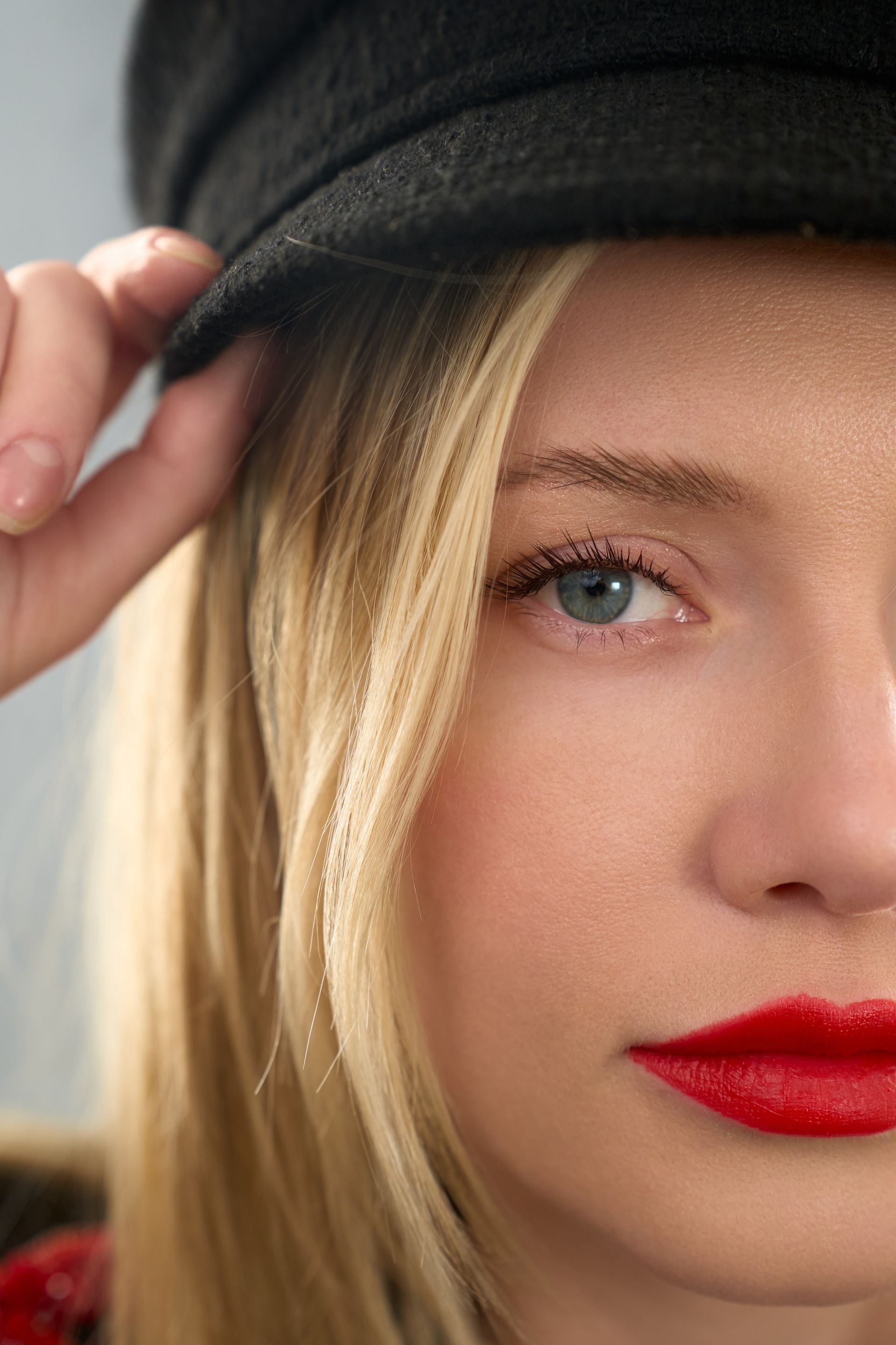 A close up of a woman wearing a hat and red lipstick