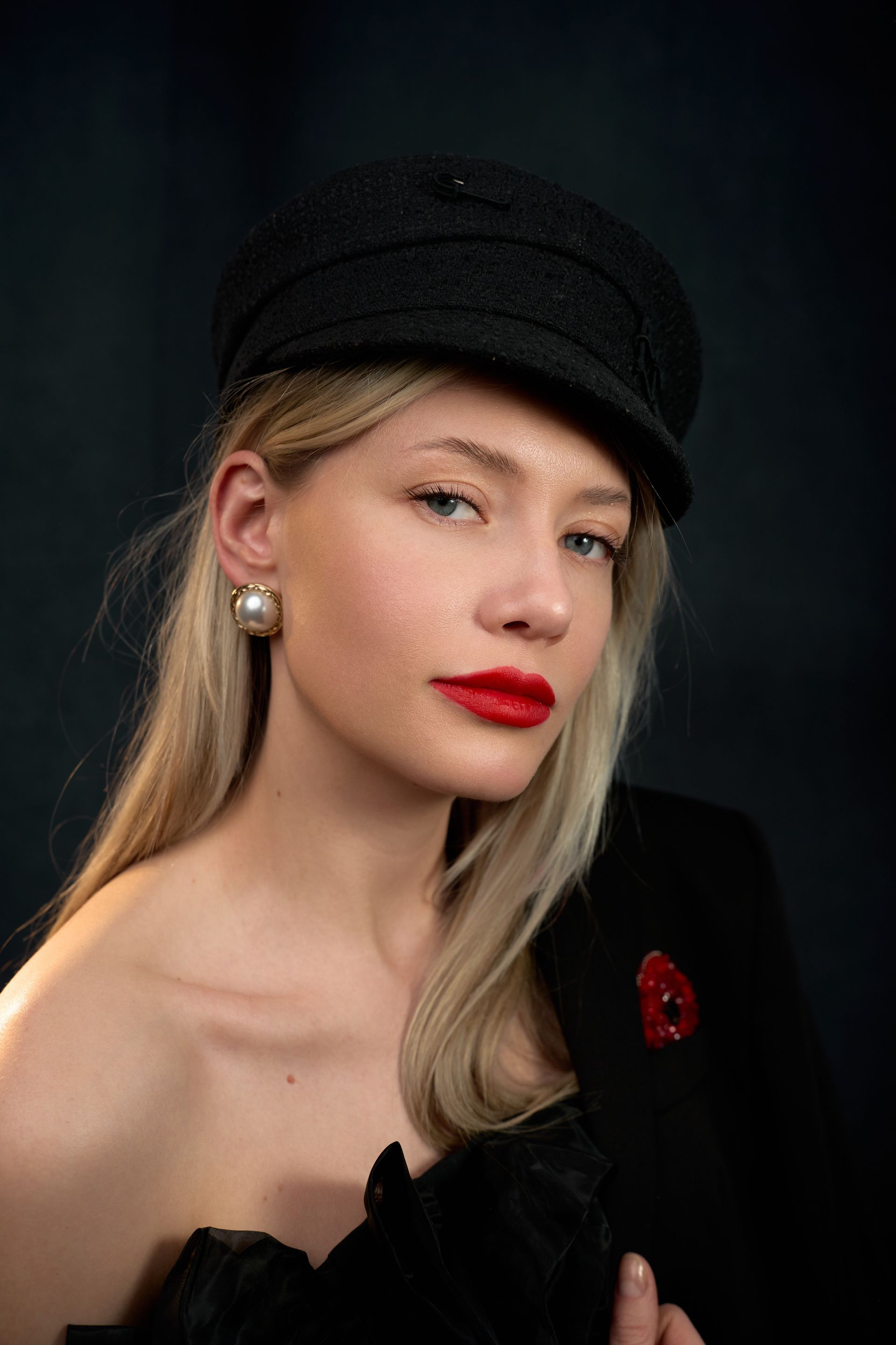 The woman is wearing a black hat and red lipstick.