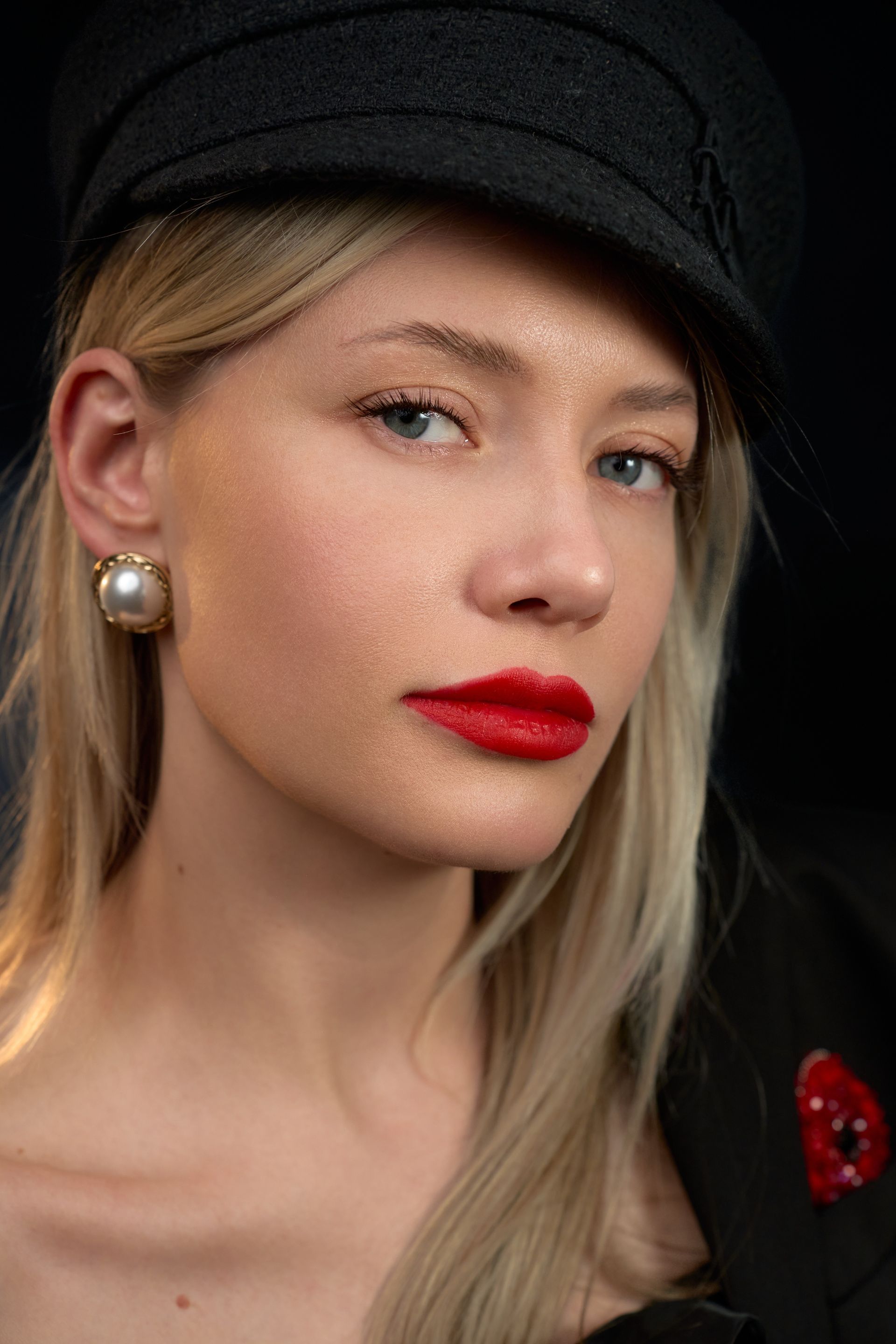 A close up of a woman wearing a hat and red lipstick.