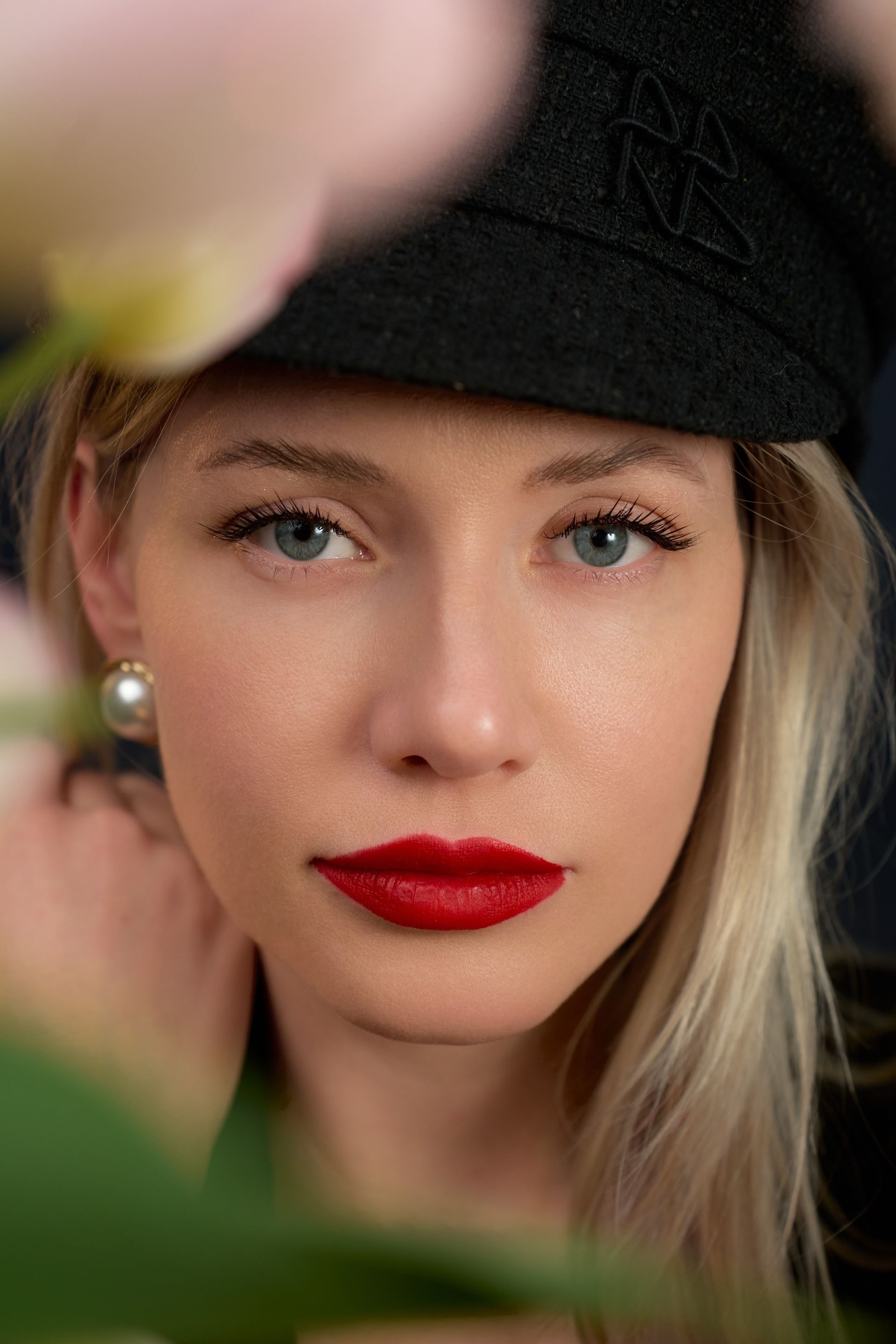 A close up of a woman wearing a hat and red lipstick.