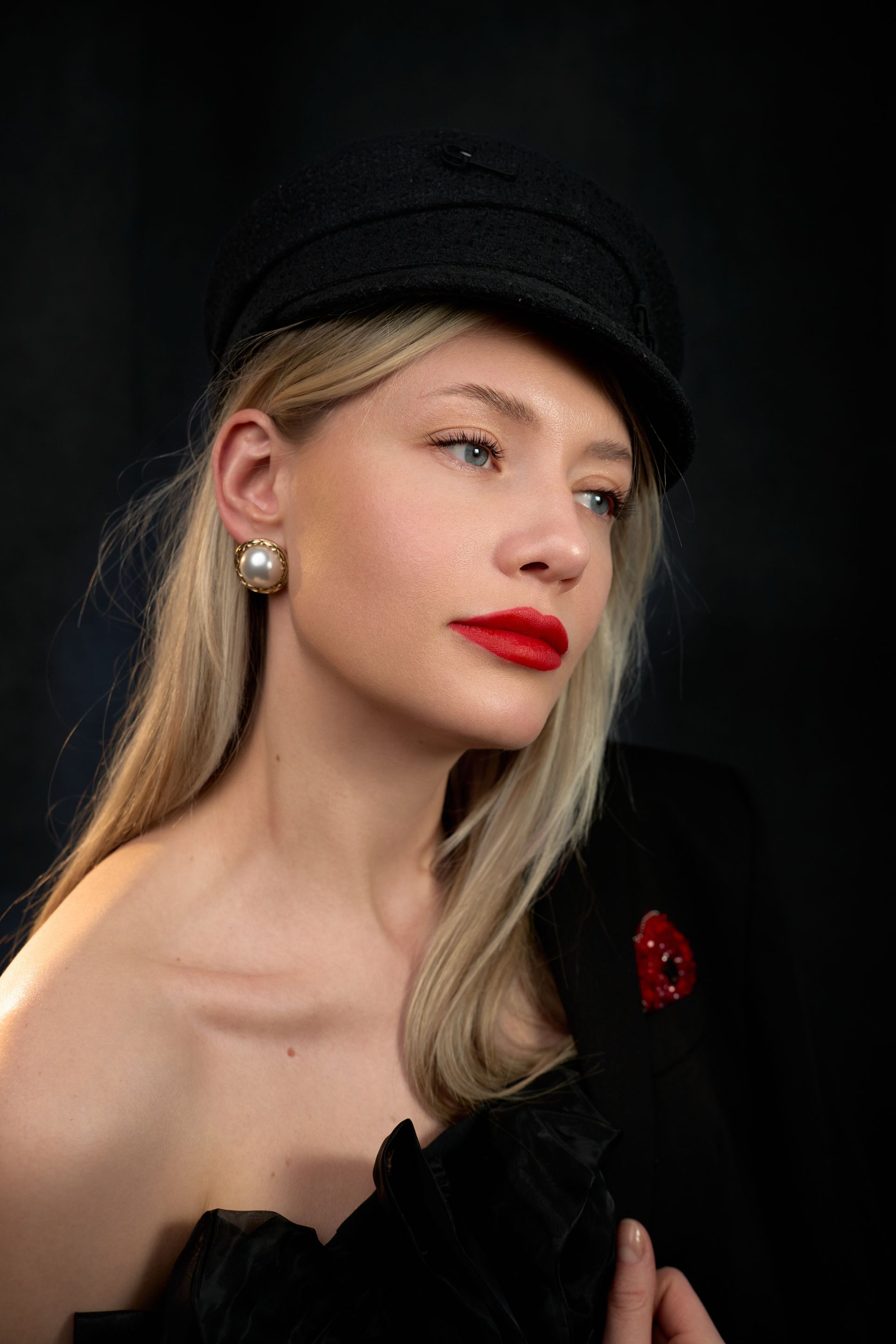 The woman is wearing a black hat and red lipstick.
