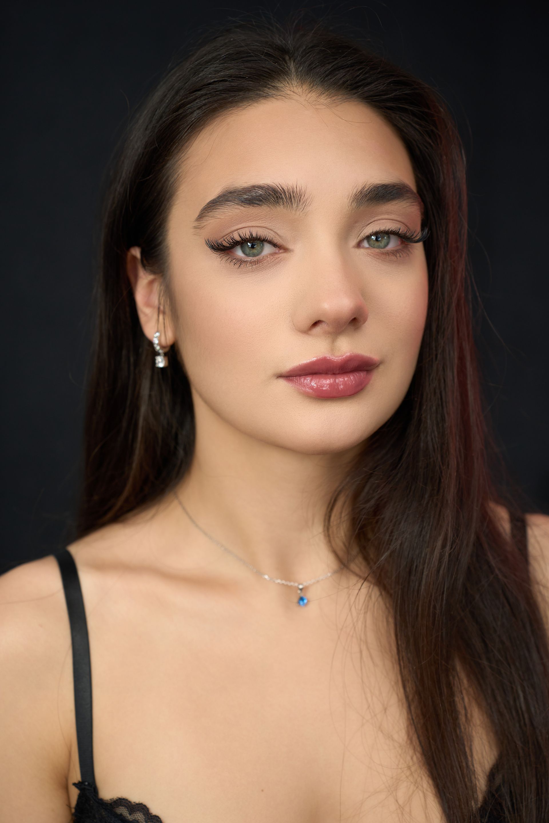 A close up of a woman wearing a necklace and earrings.