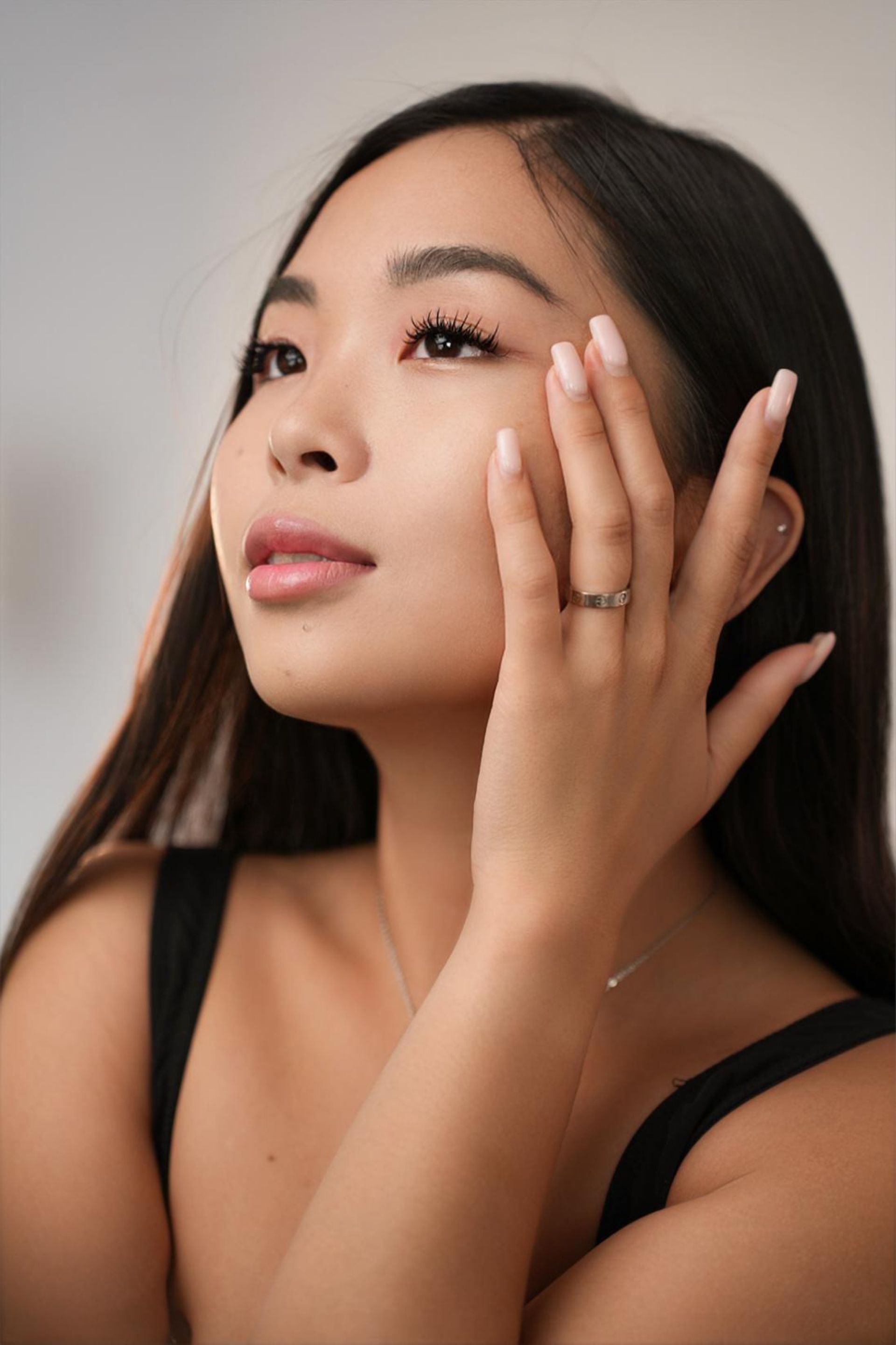 The woman is wearing a ring on her finger and touching her face.
