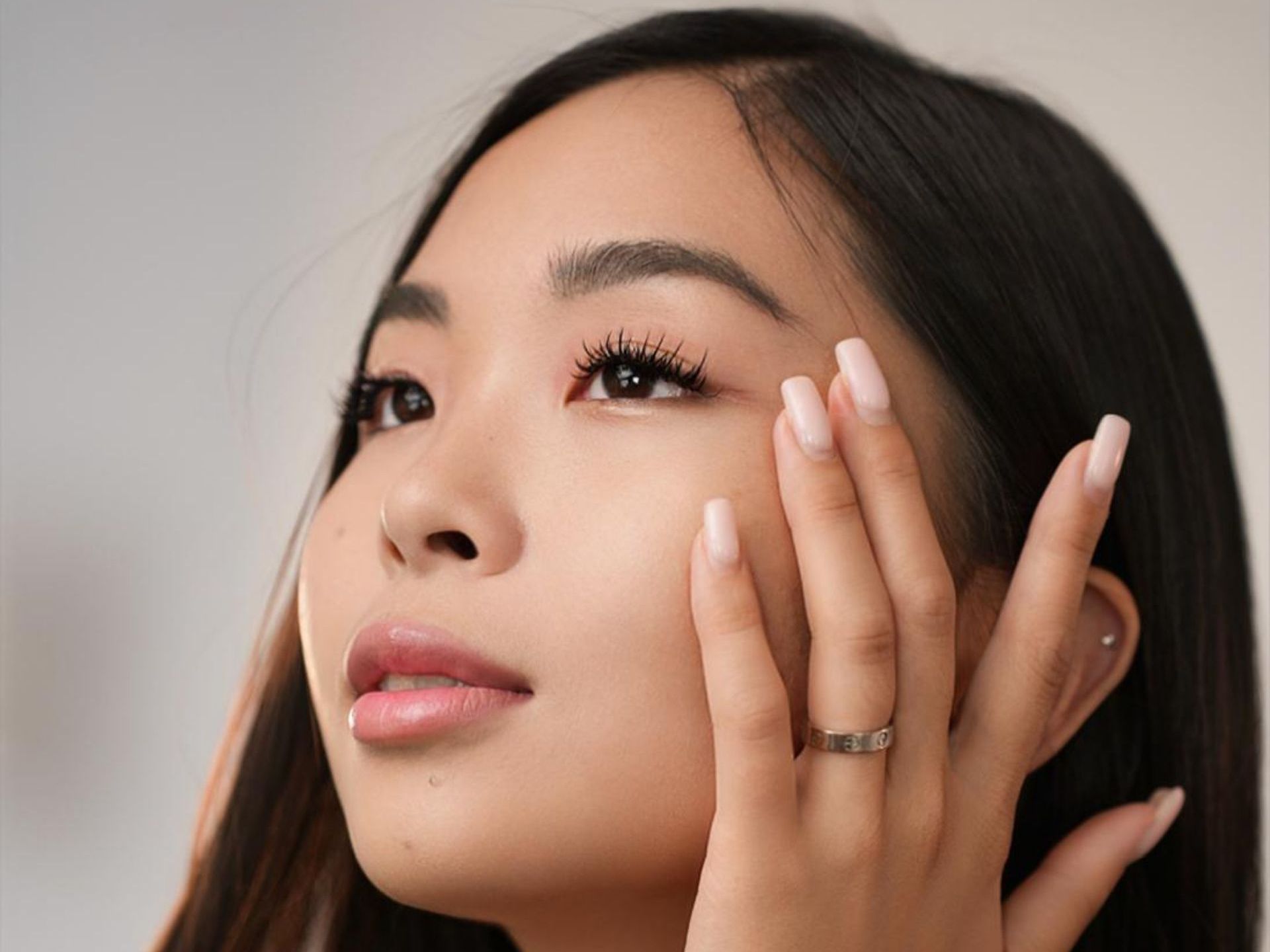 The woman is wearing a ring on her finger and touching her face.