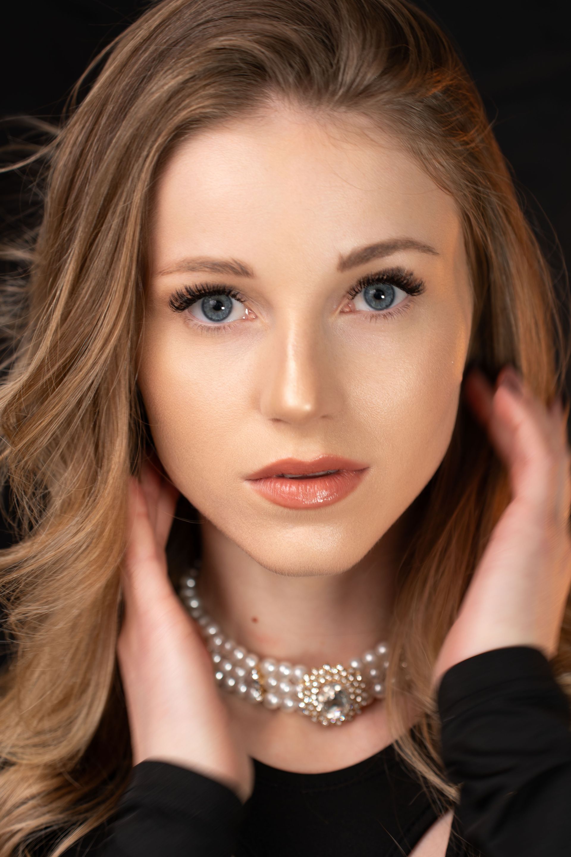 A close up of a woman wearing a pearl necklace.