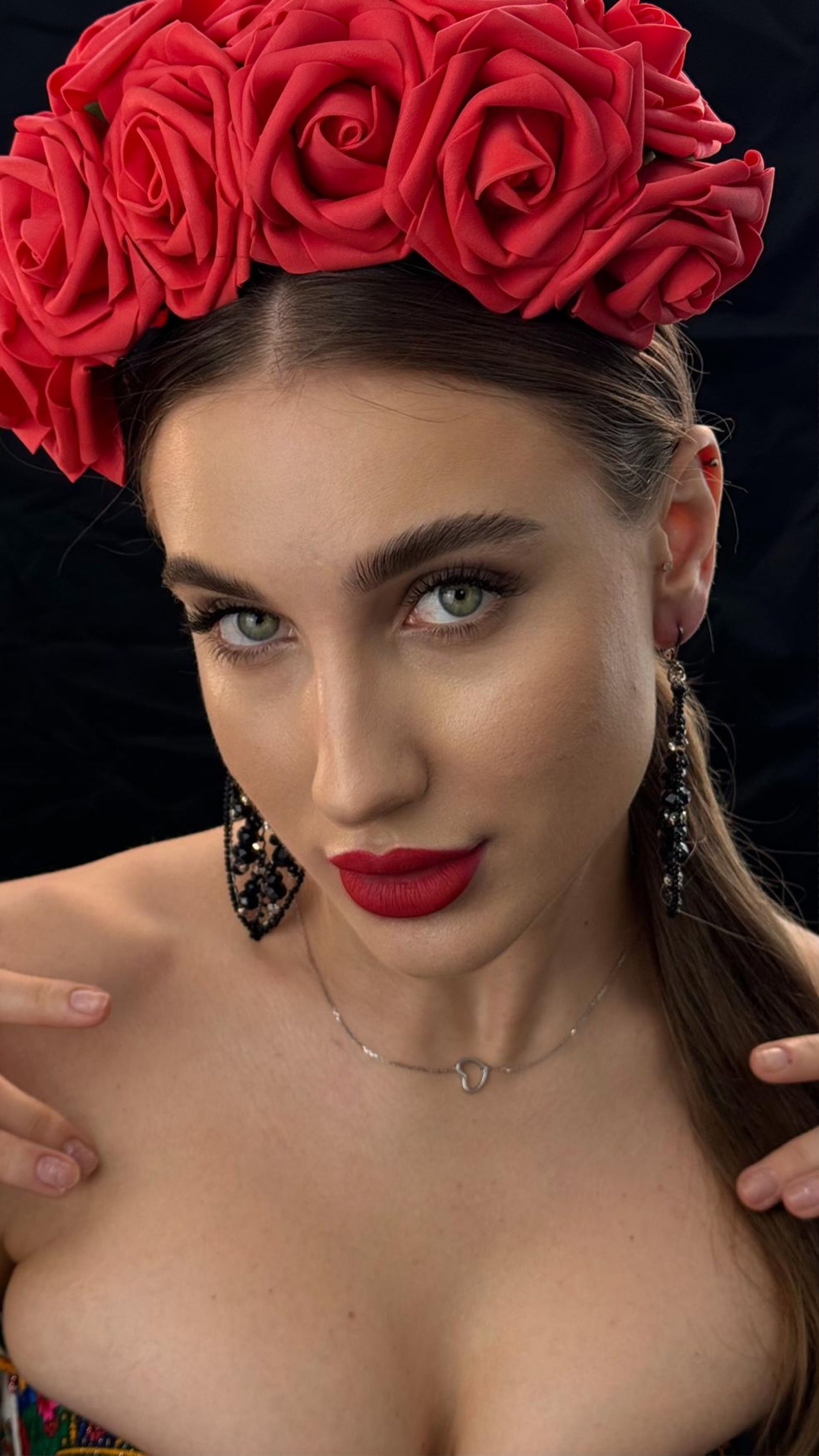 A woman is wearing a red flower crown on her head.