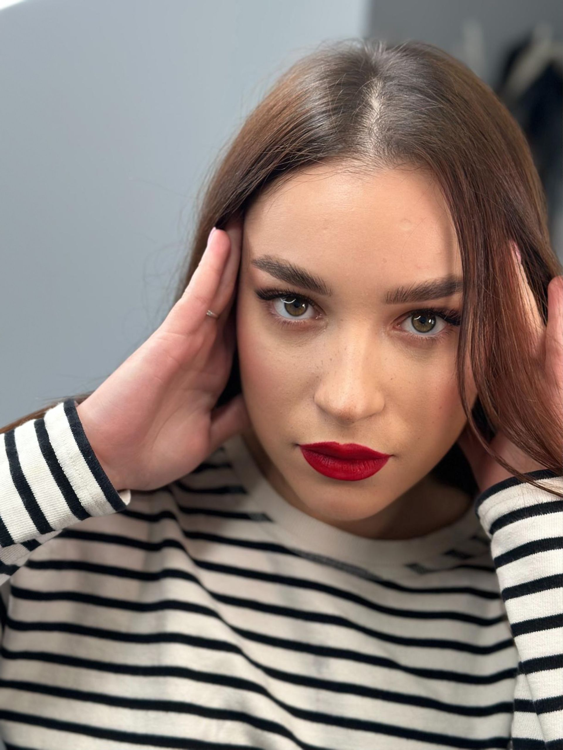 The woman is wearing a striped shirt and red lipstick.