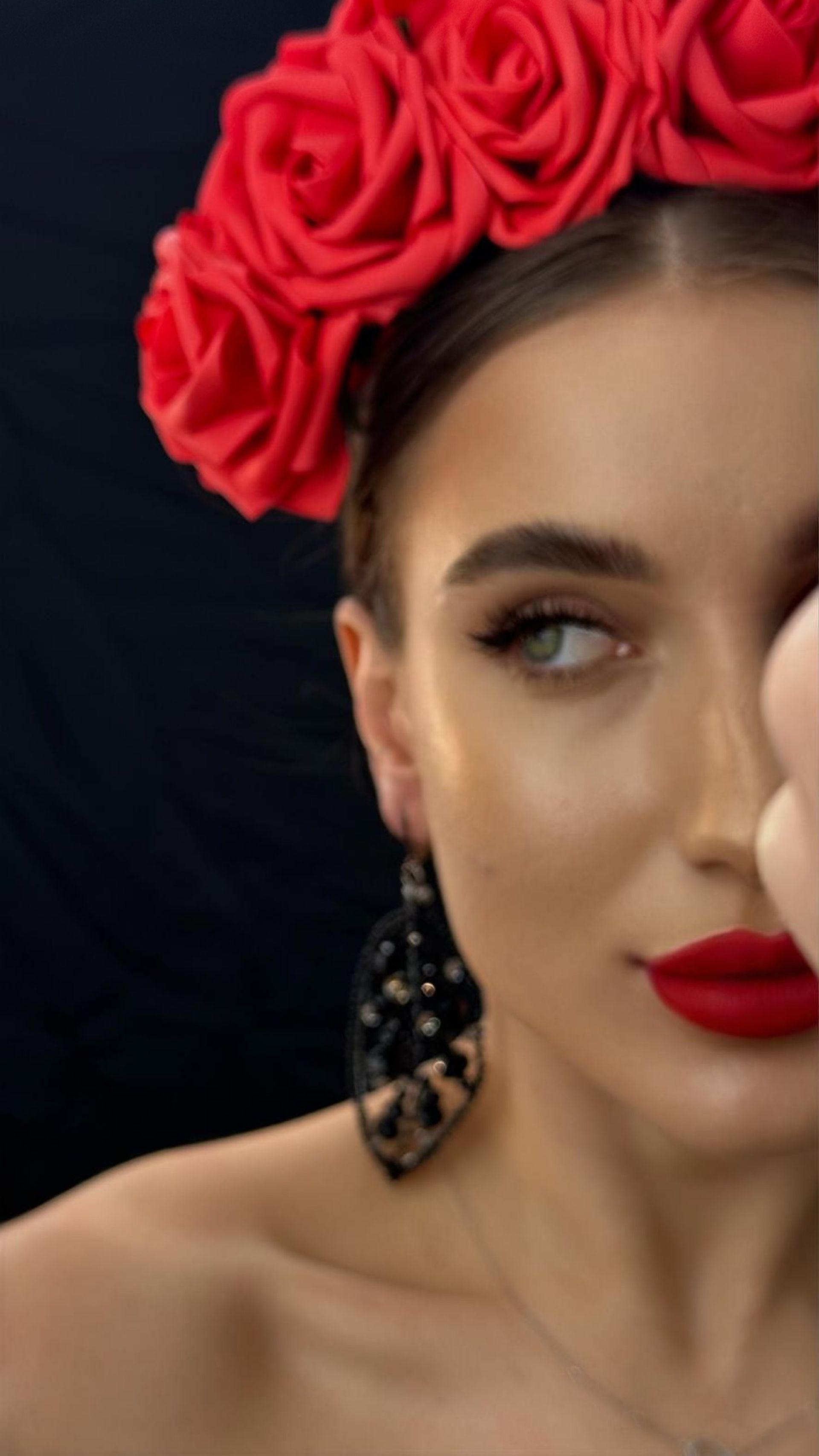 A woman wearing a headband of red roses and black earrings