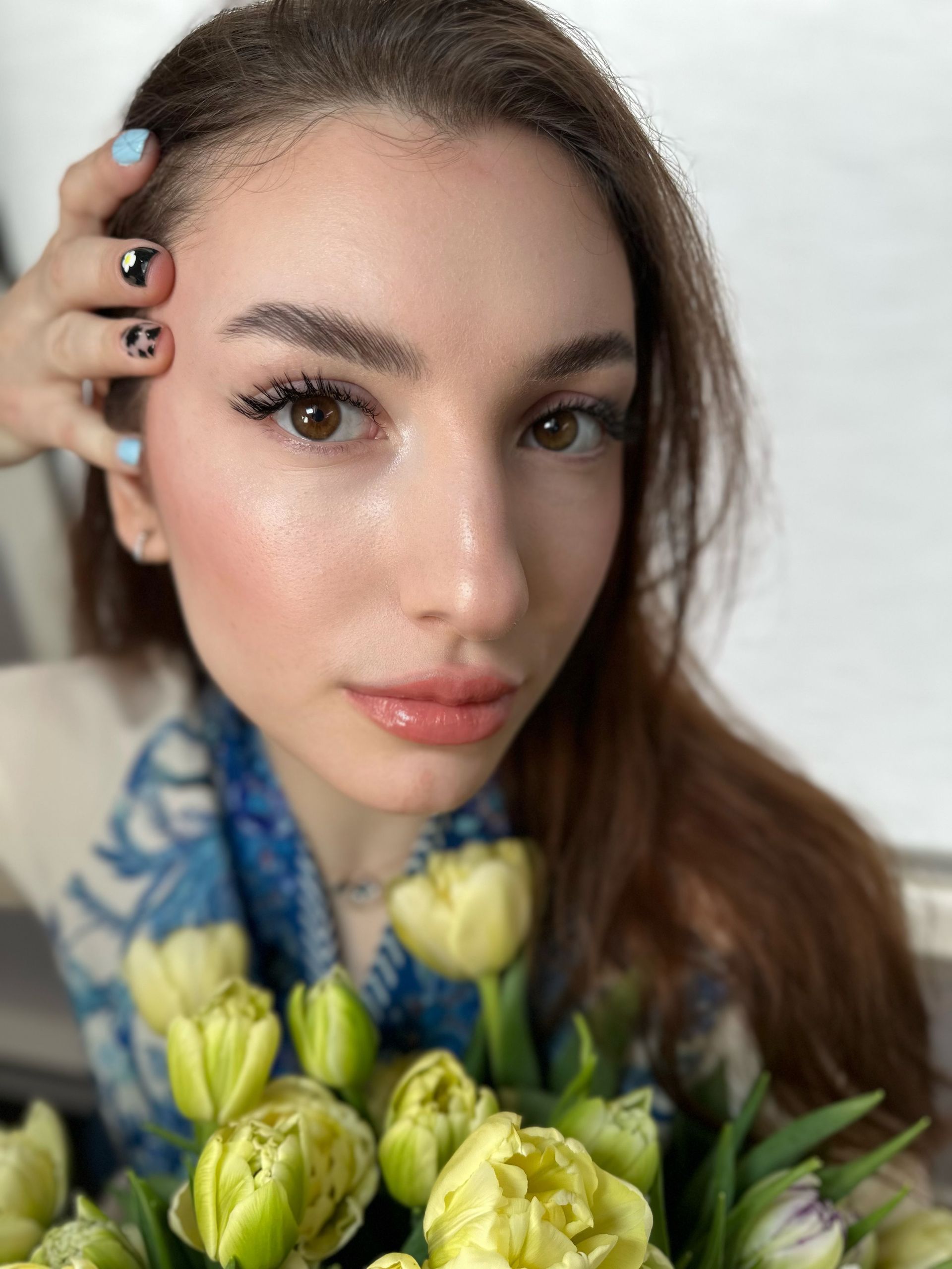 A woman is holding a bouquet of flowers in front of her face.