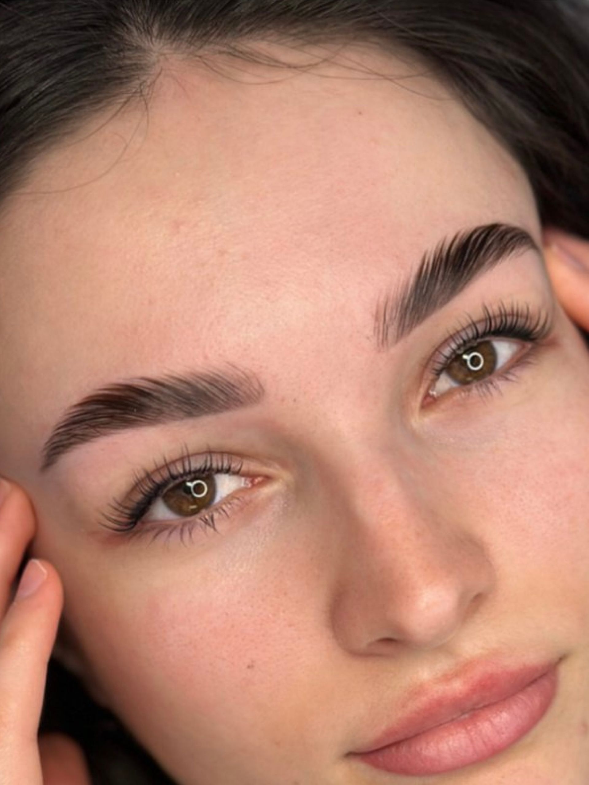 A close up of a woman 's face with a hand on her forehead.
