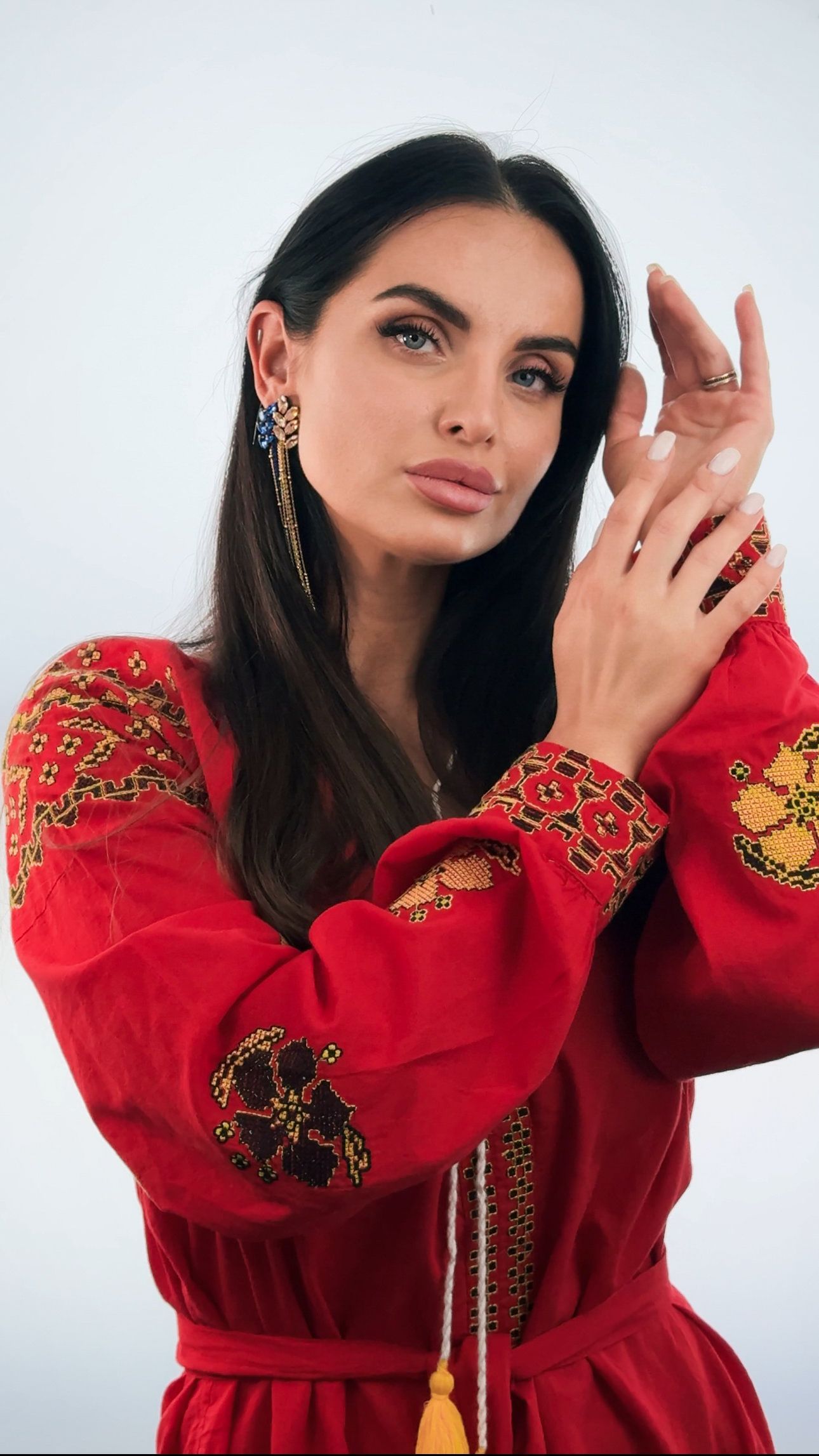 The woman is wearing a red dress with embroidery on the sleeves.