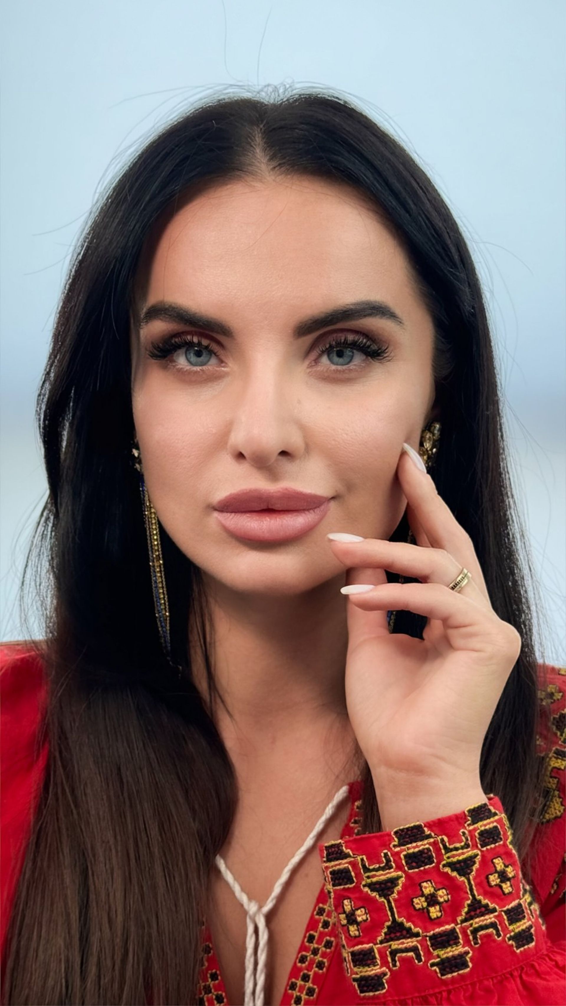 A woman in a red dress is holding her hand to her face.