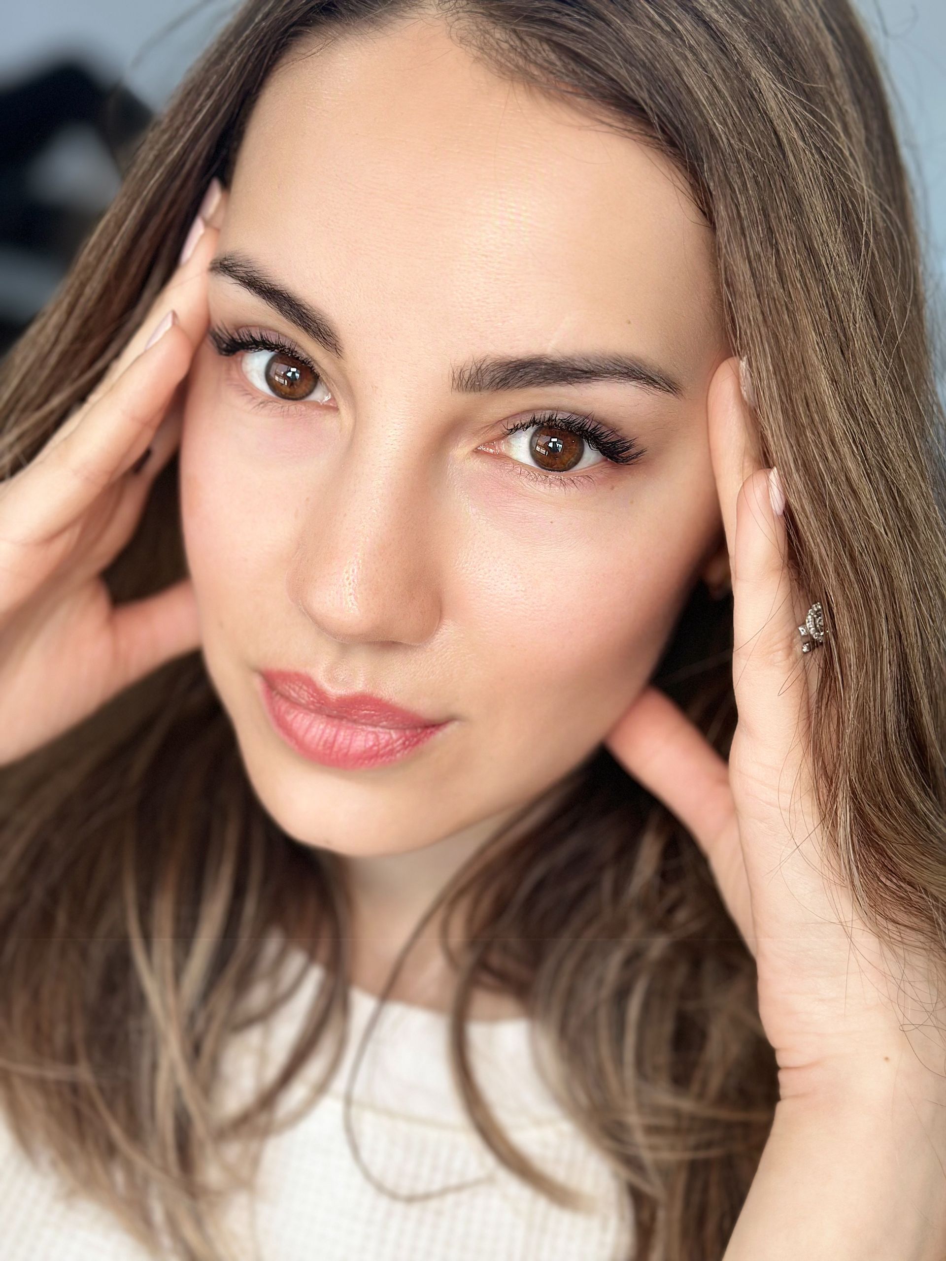 A close up of a woman 's face with her hands on her forehead.