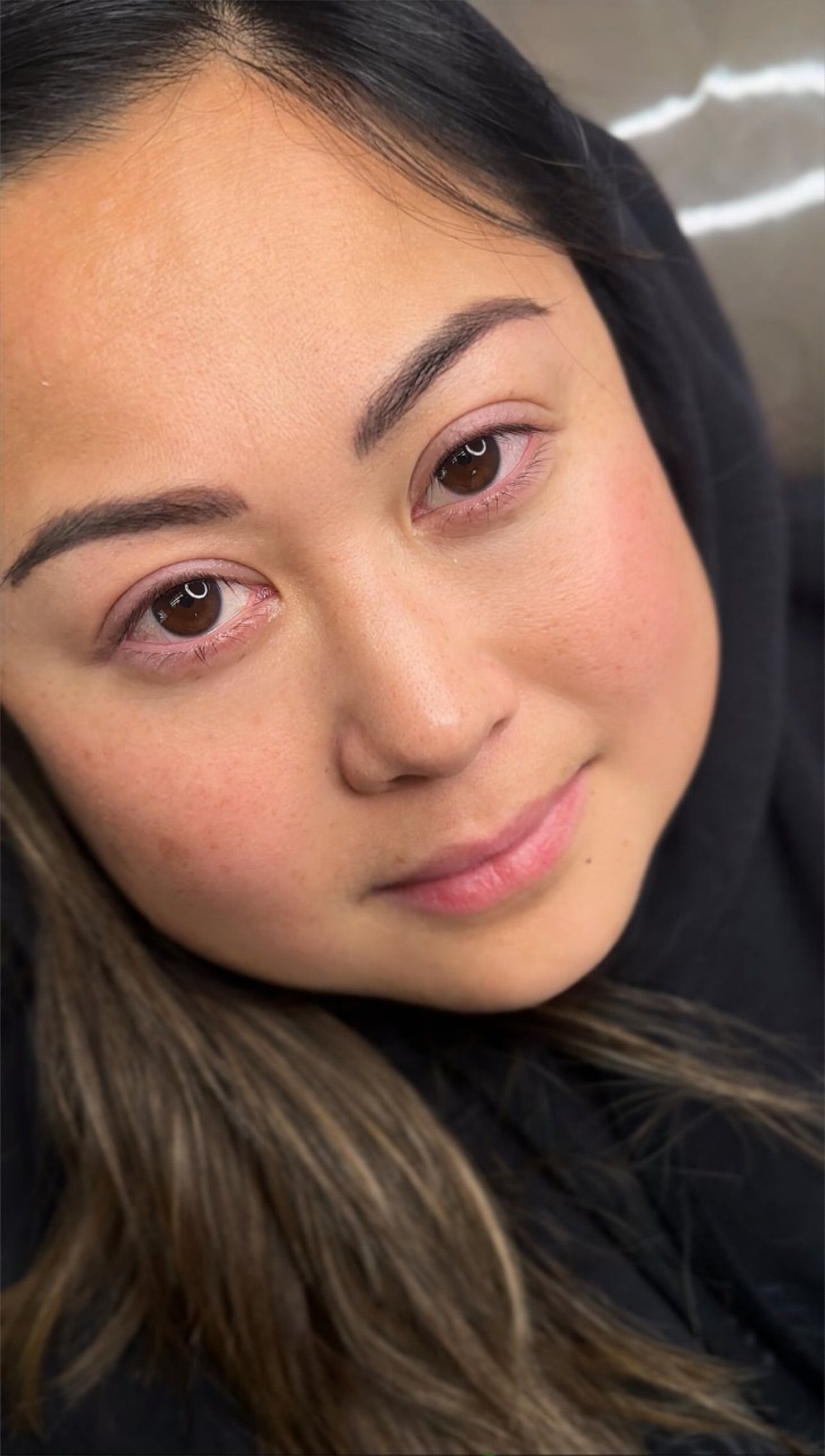 A close up of a woman 's face with a black hoodie on.