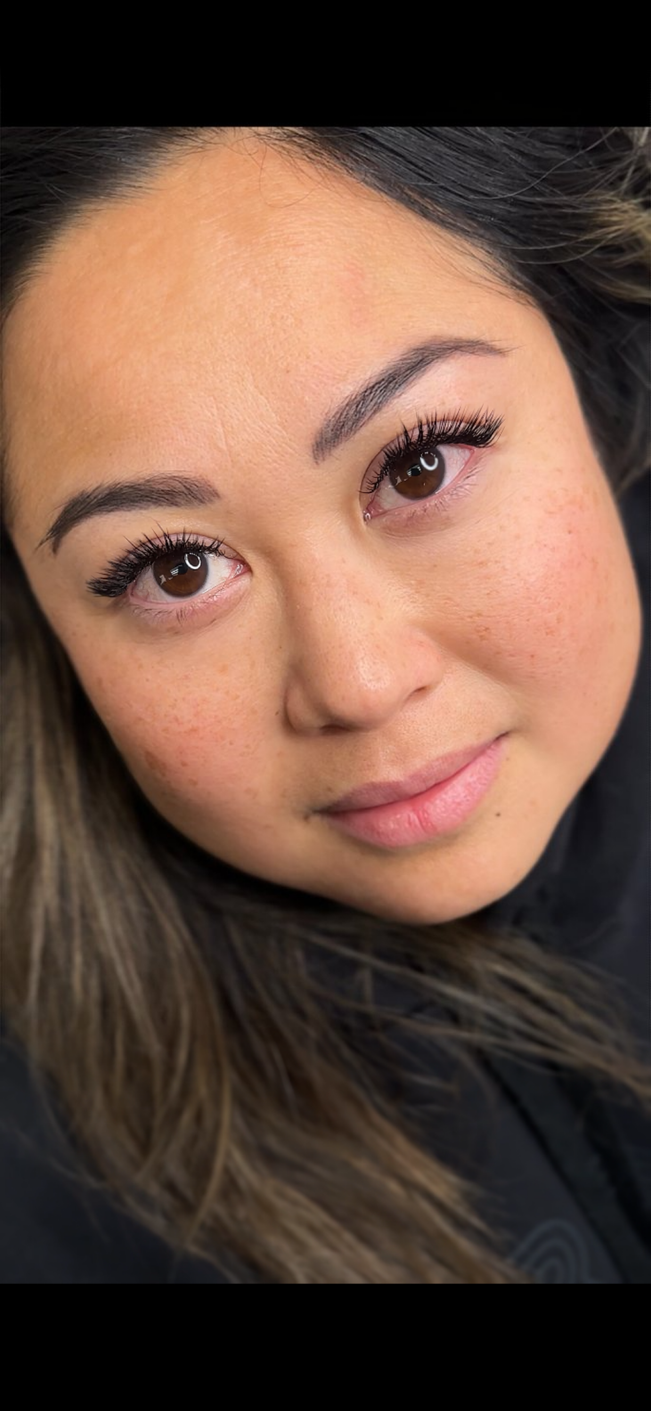 A close up of a woman 's face with long eyelashes.