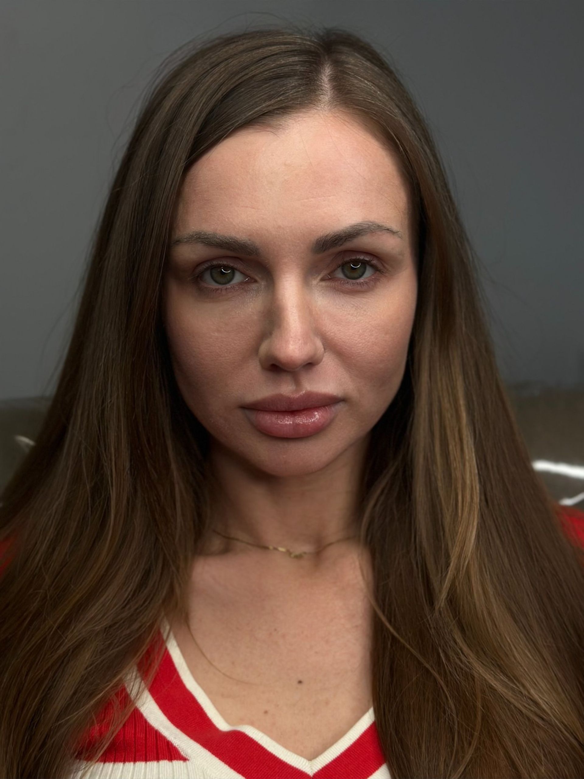 A woman with long brown hair is wearing a red and white shirt.
