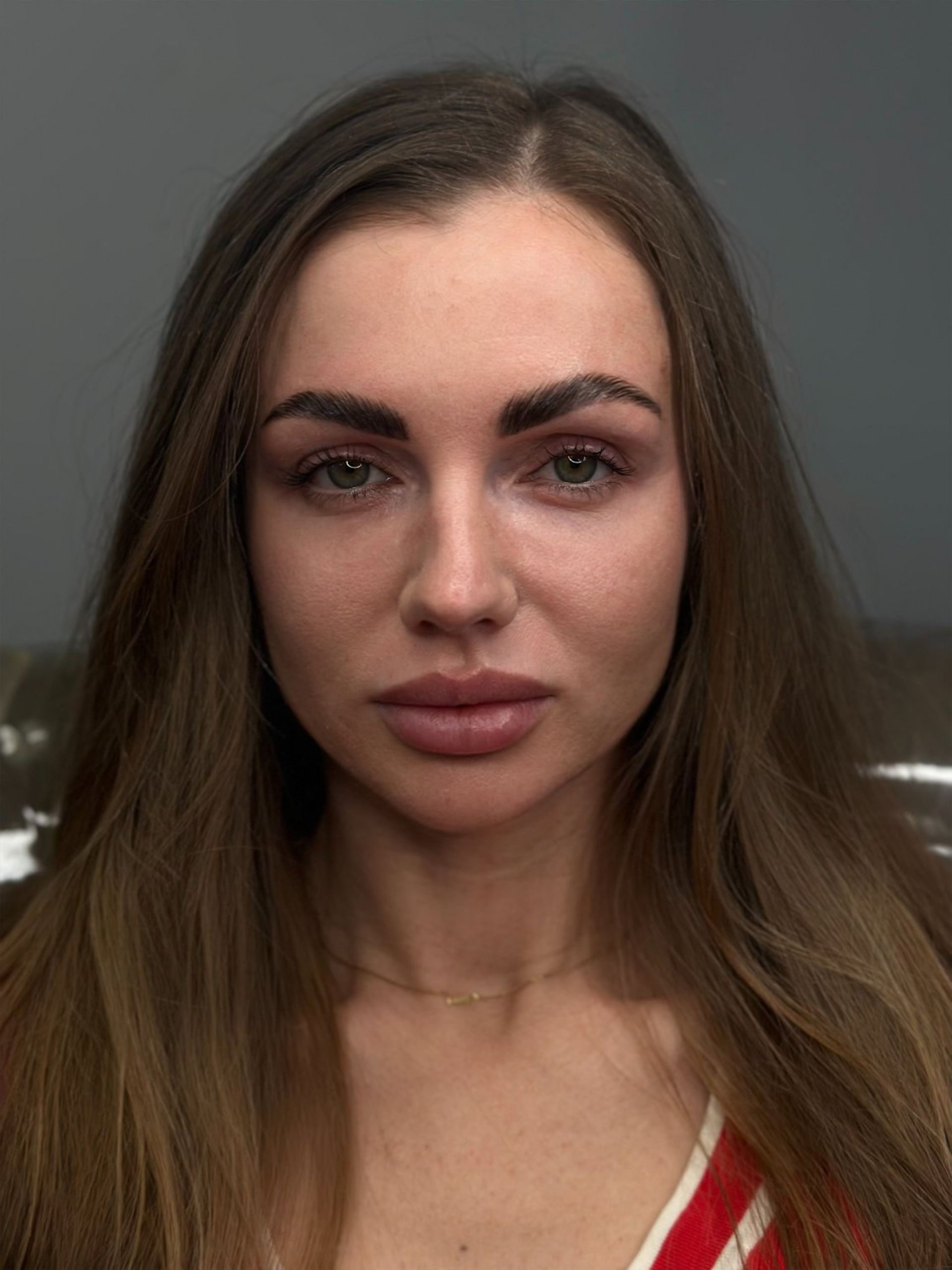 A woman with long hair and a nose ring is looking at the camera.