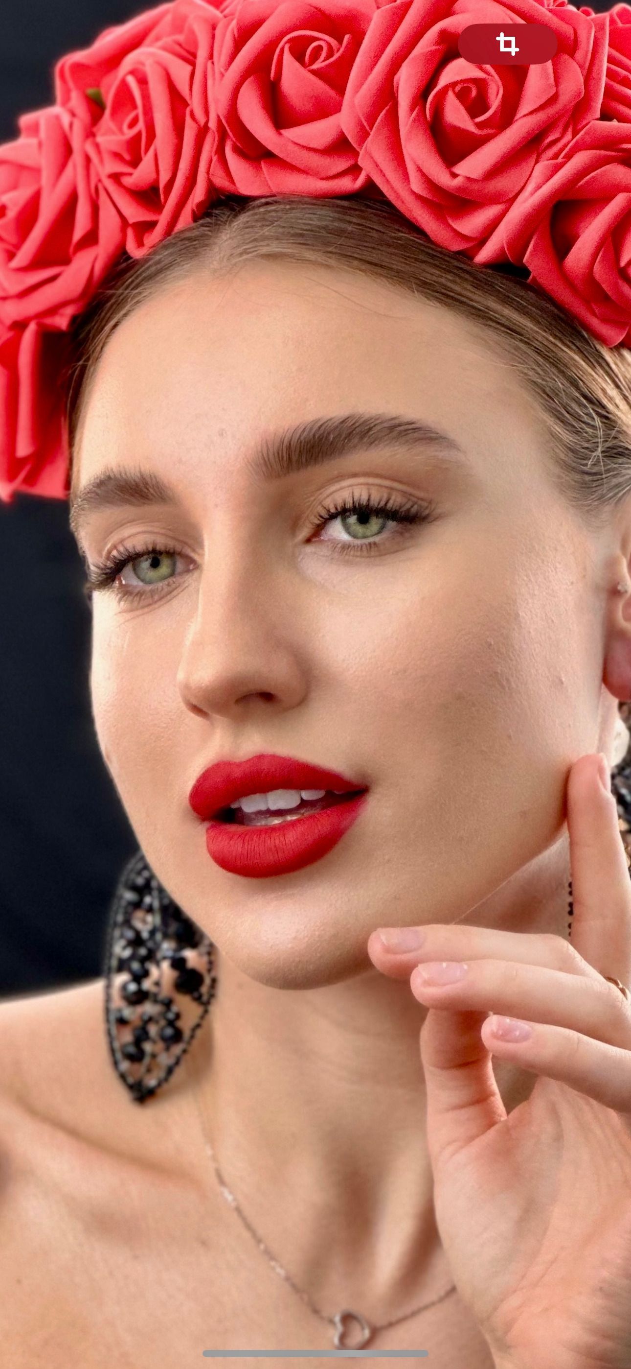 A woman wearing a red flower crown and red lipstick.
