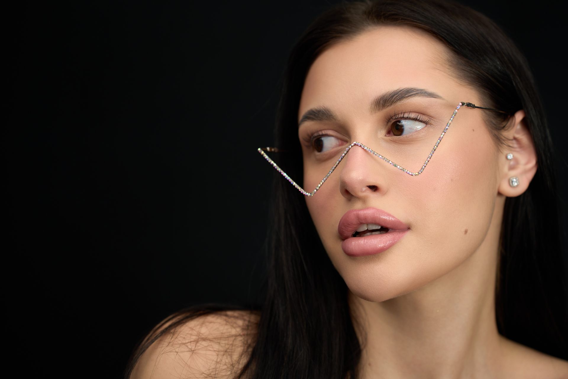 A close up of a woman wearing glasses on a black background.