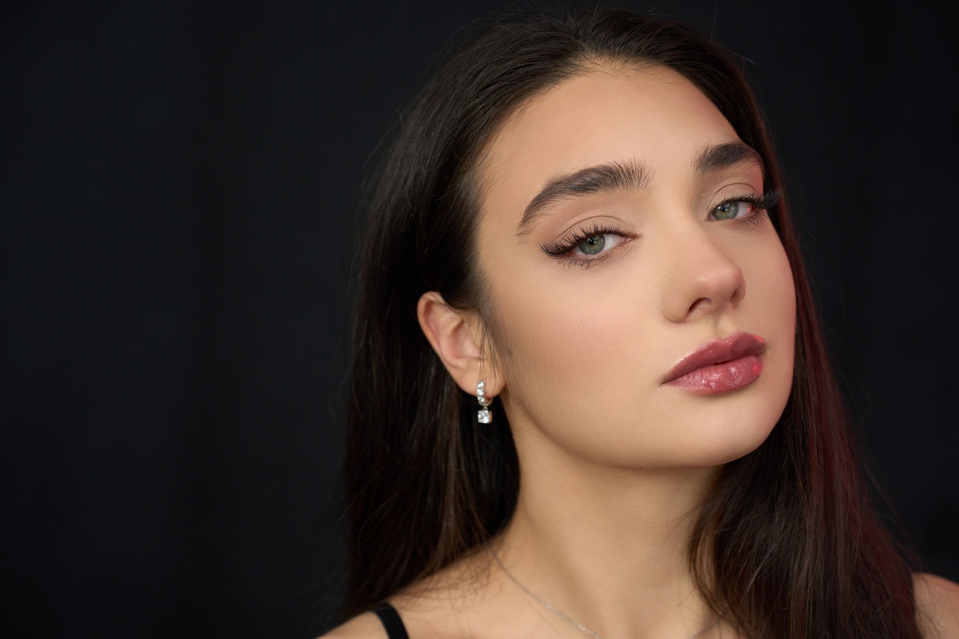 A close up of a woman 's face wearing earrings and a black top.