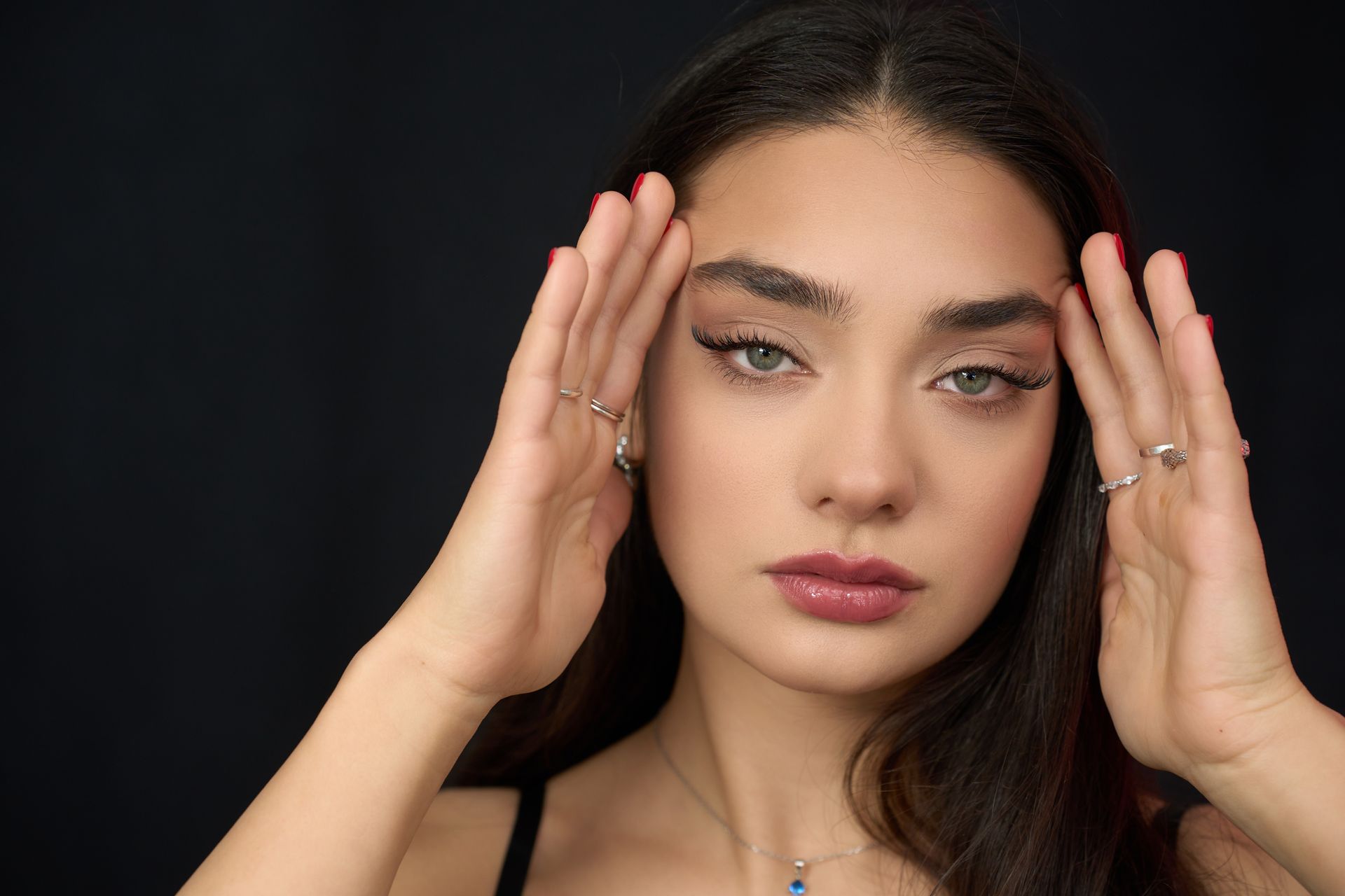 A close up of a woman 's face with her hands on her forehead.