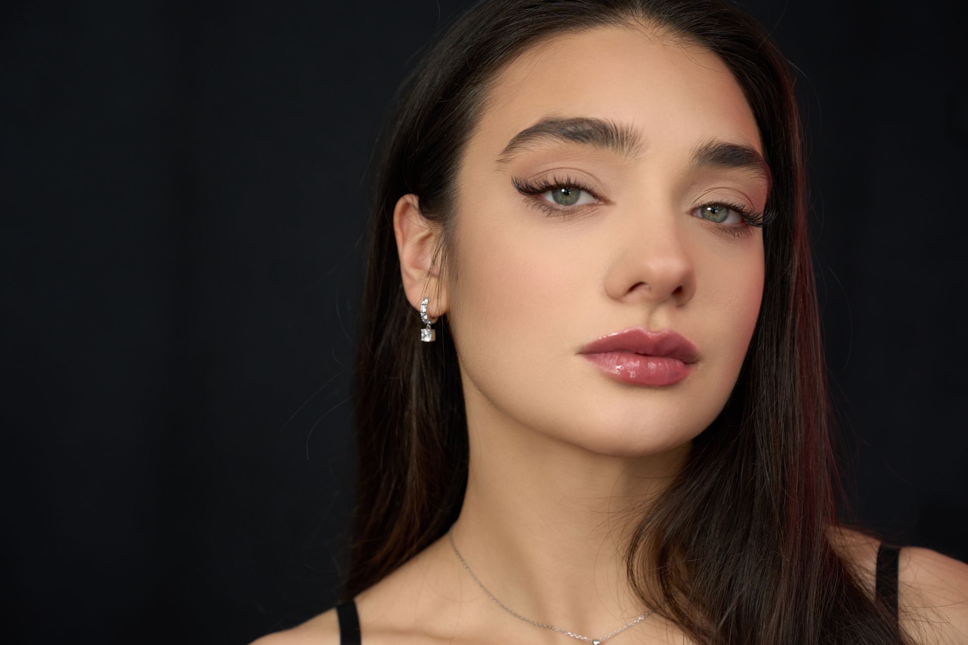 A close up of a woman 's face wearing earrings and a necklace.