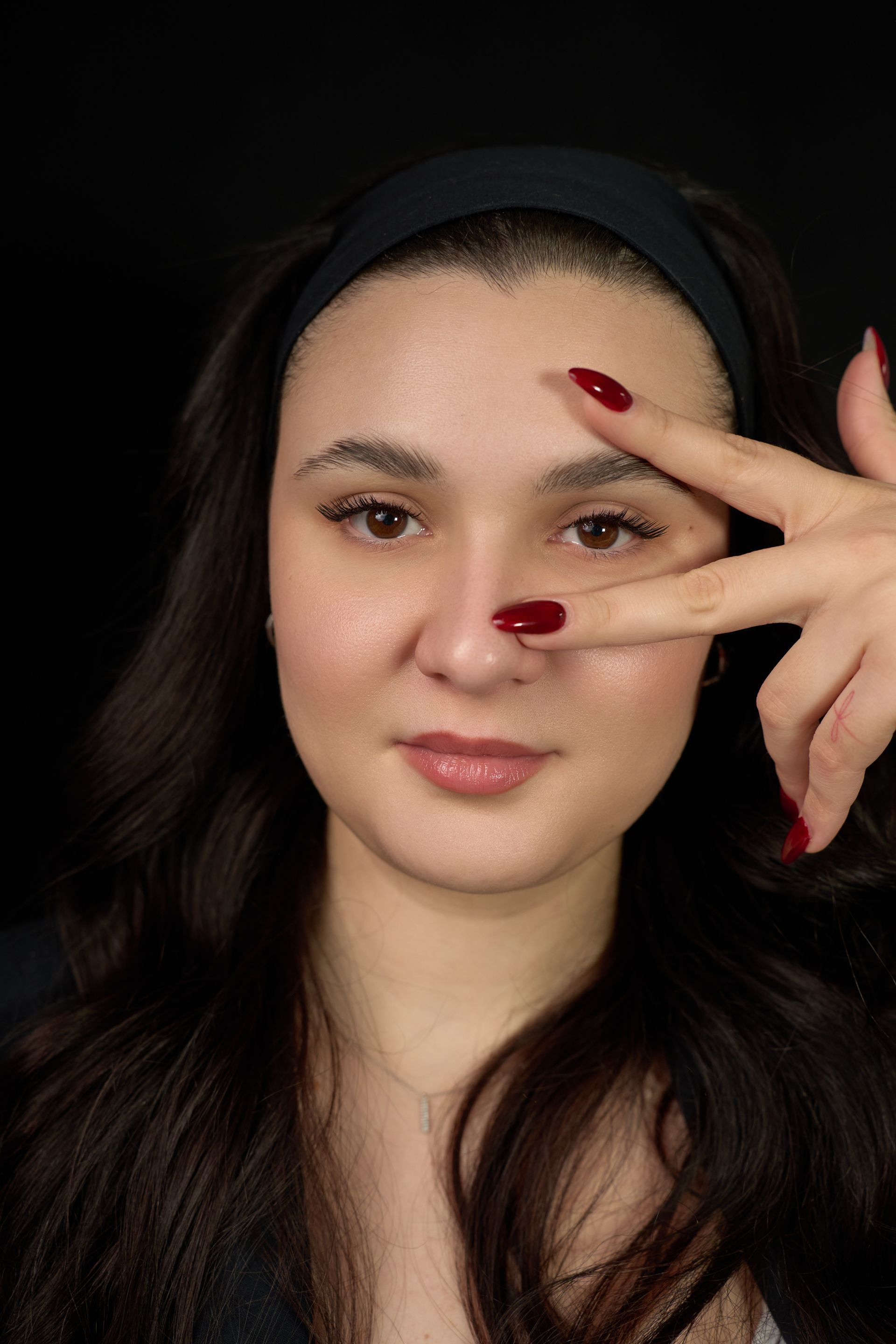 A woman with red nails is covering her face with her hand.