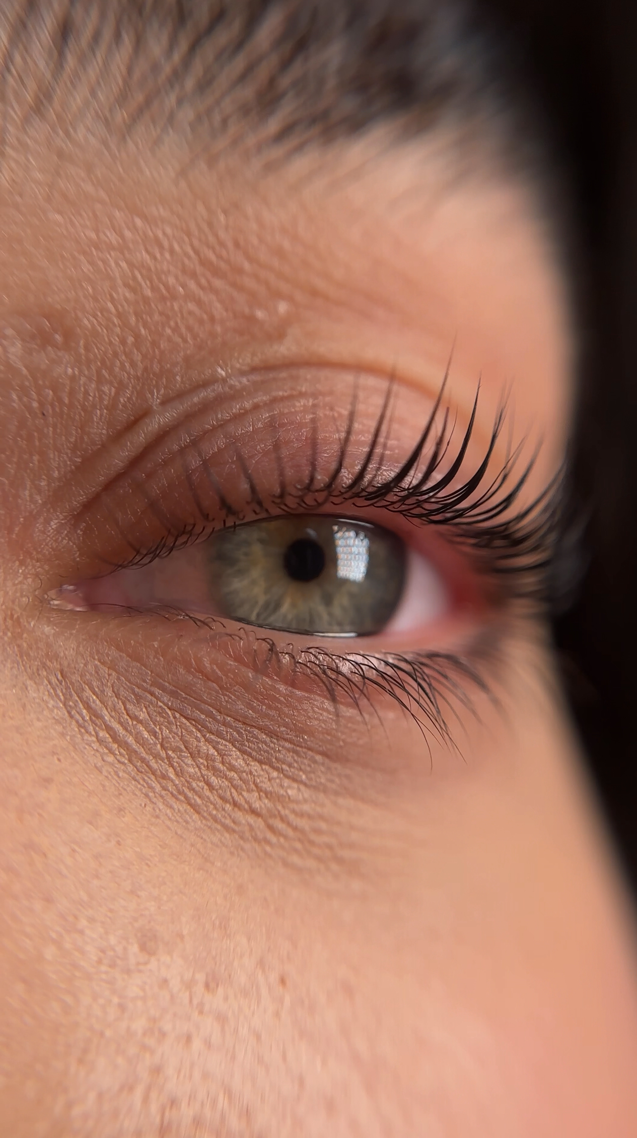 A close up of a woman 's green eye with long eyelashes.