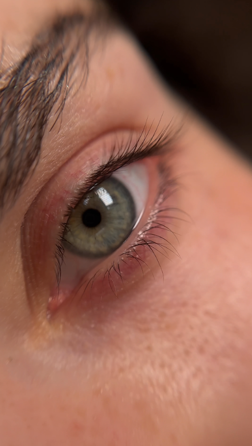 A close up of a woman 's green eye with long eyelashes.