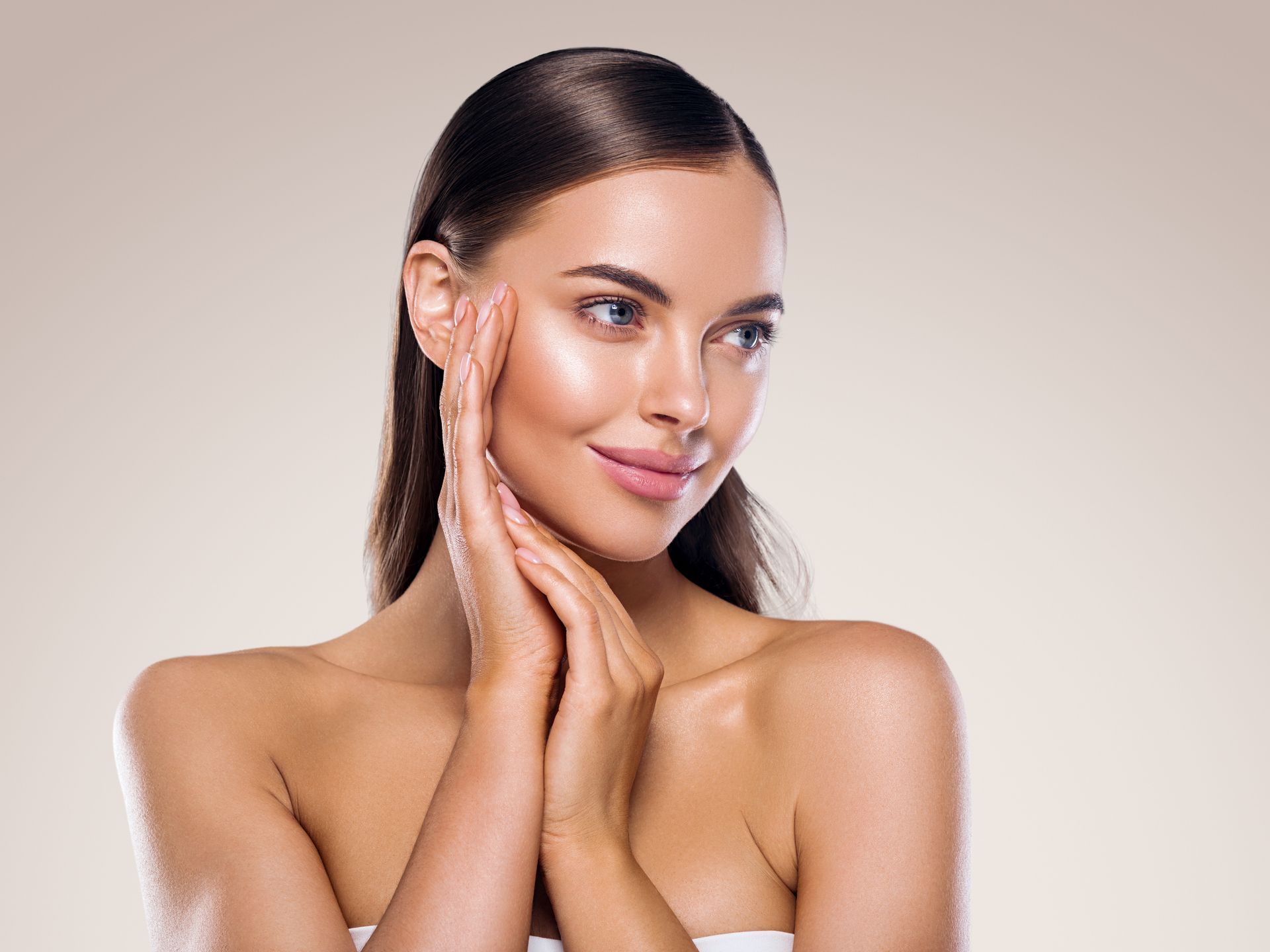 A woman is covering her ears with her hands and looking at the camera.