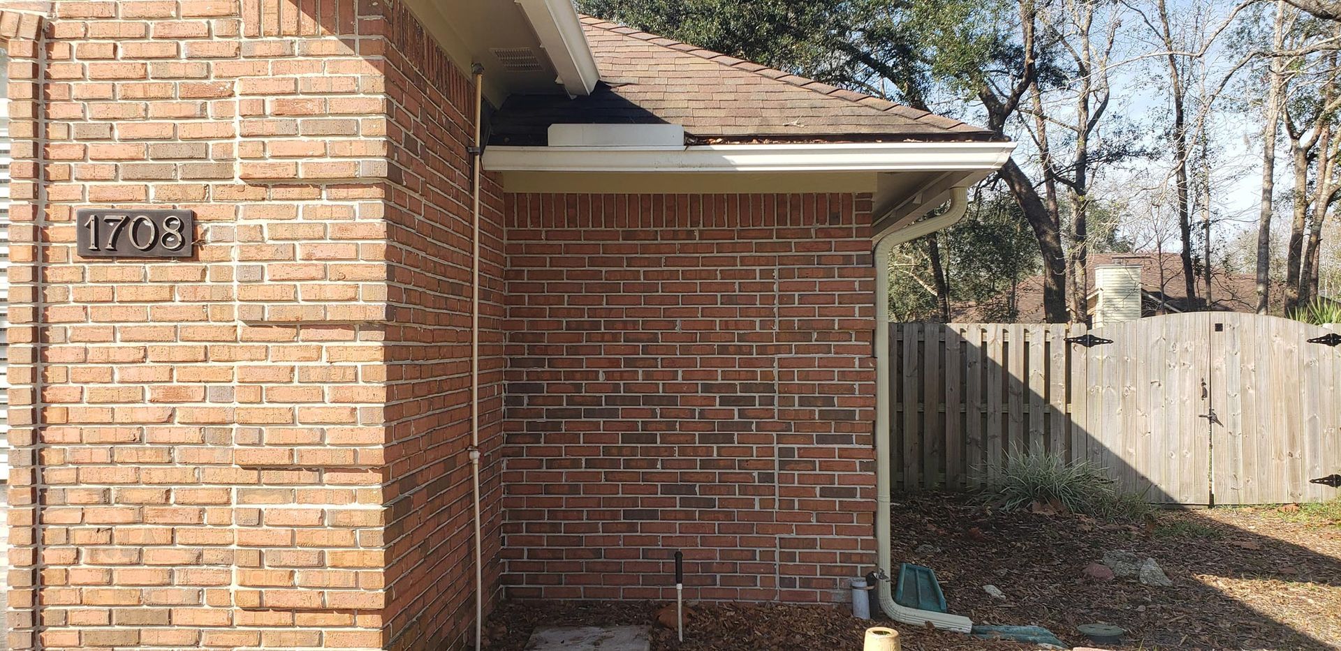 A brick house with a wooden fence in the background.