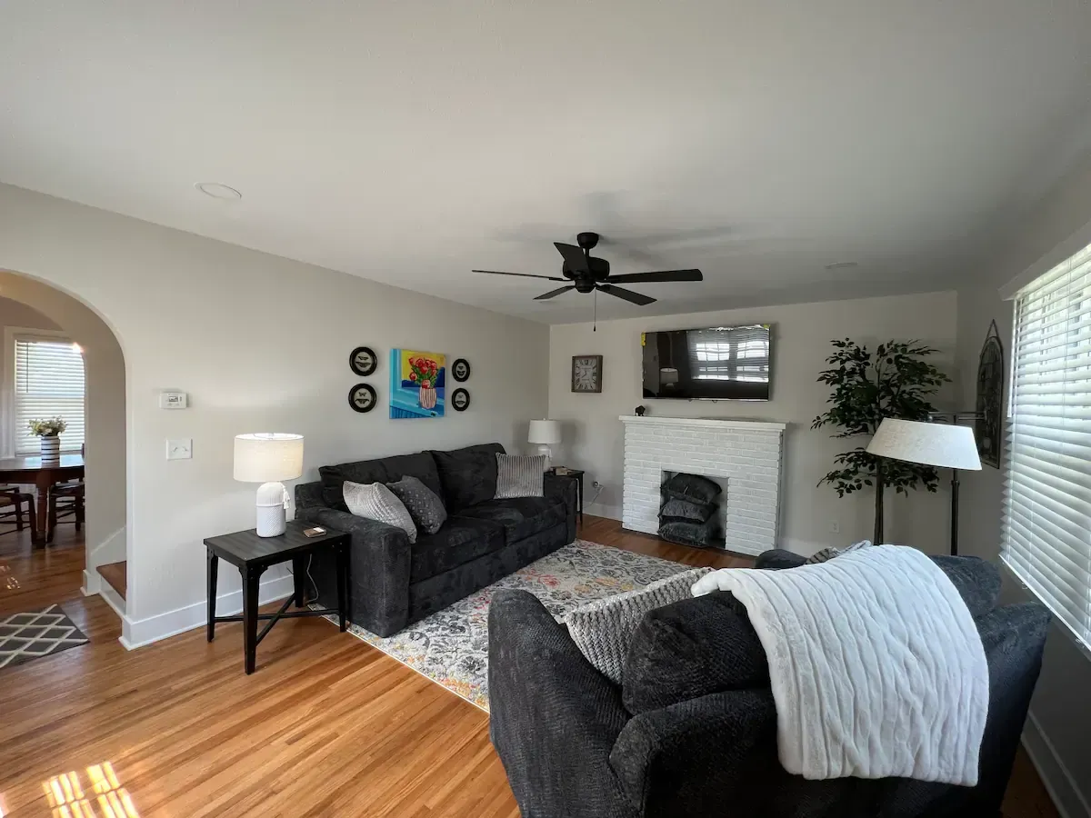 A living room with a couch , chair , fireplace and ceiling fan.